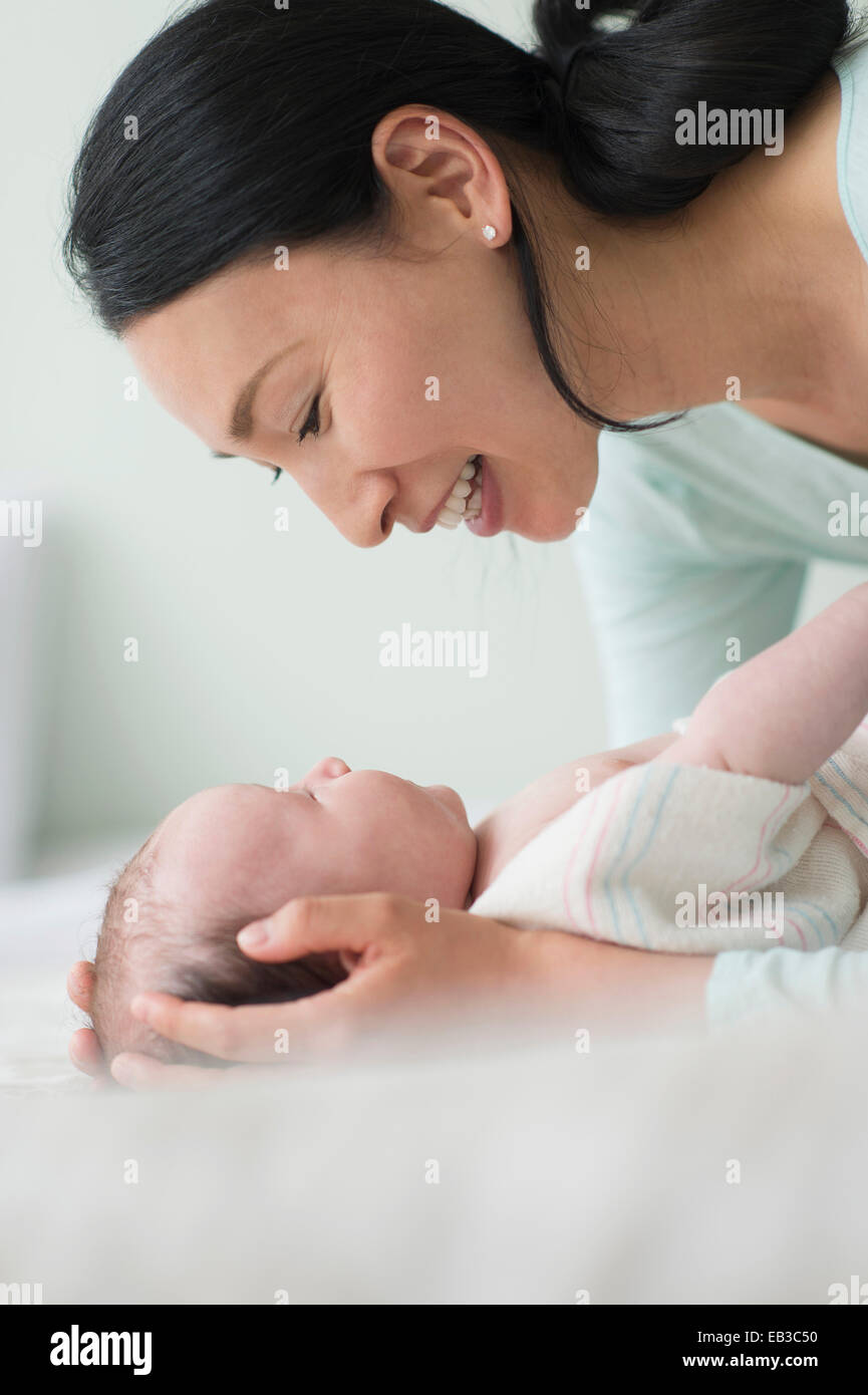 Asian mother holding baby on bed Banque D'Images