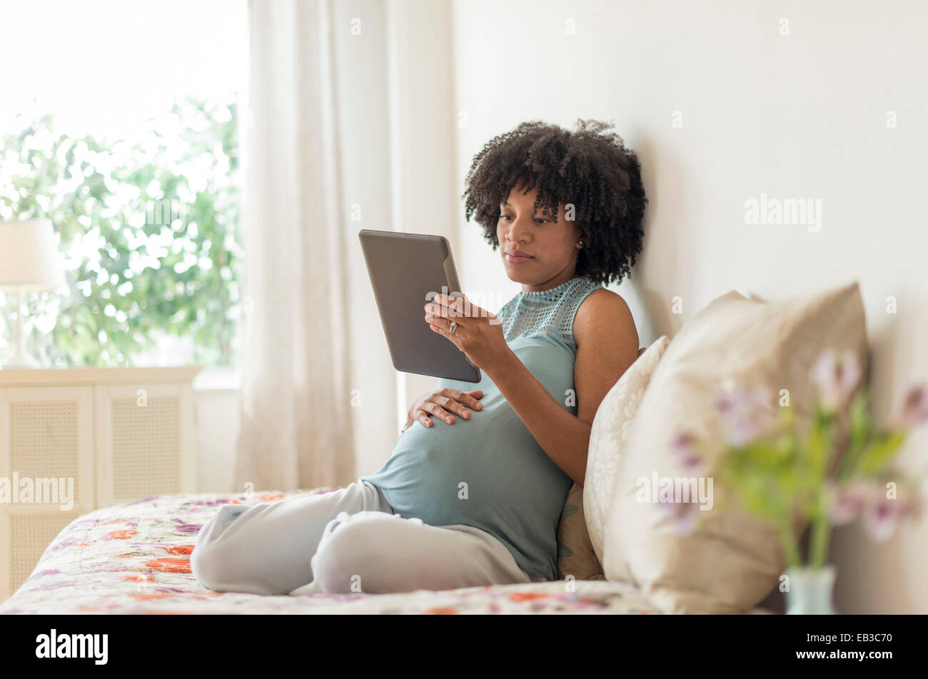 Pregnant African American mother using digital tablet in bed Banque D'Images