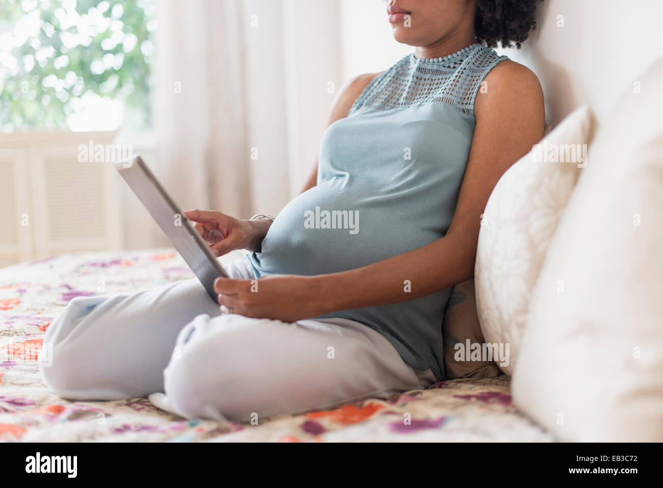 Pregnant African American mother using digital tablet in bed Banque D'Images