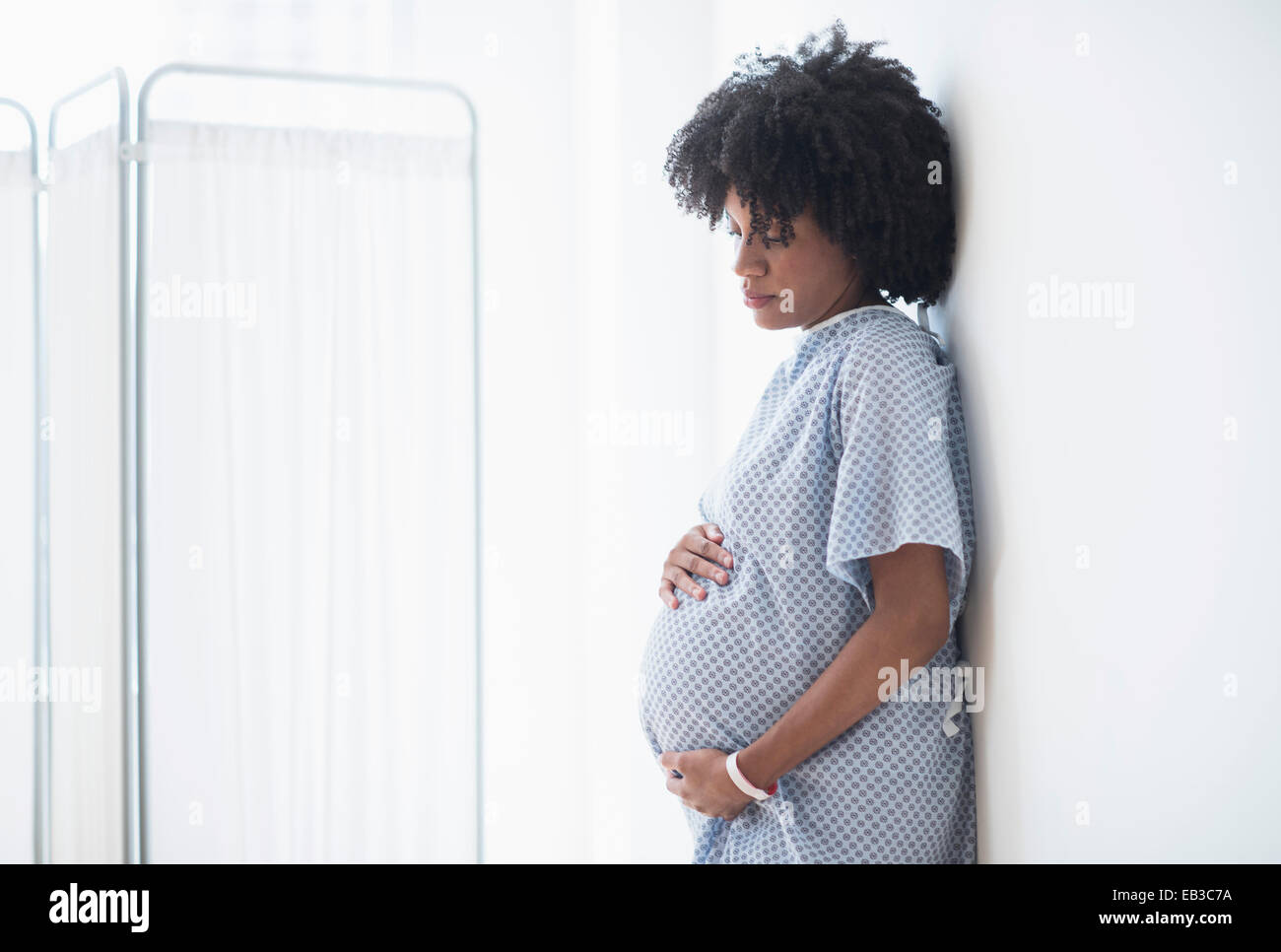 Pregnant African American mother holding stomach in hospital Banque D'Images