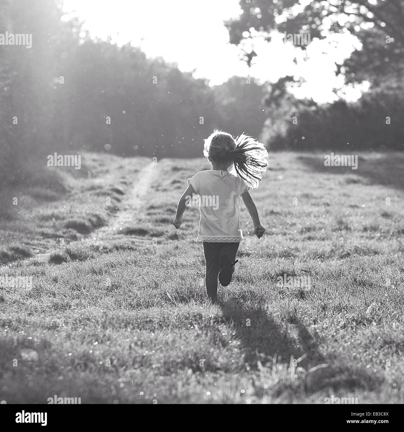 Vue arrière du girl running in rural landscape Banque D'Images