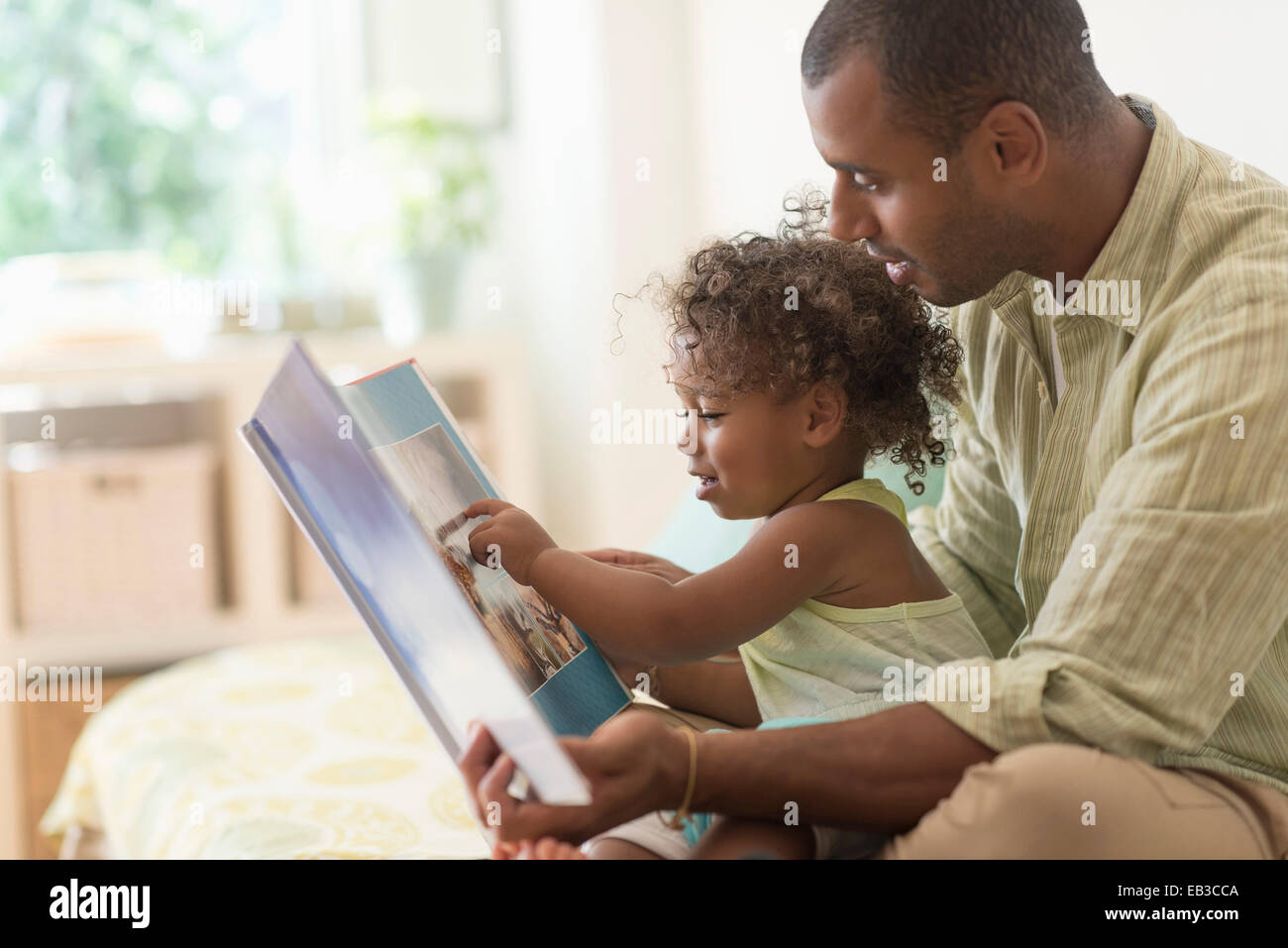 Père et fille reading book on bed Banque D'Images