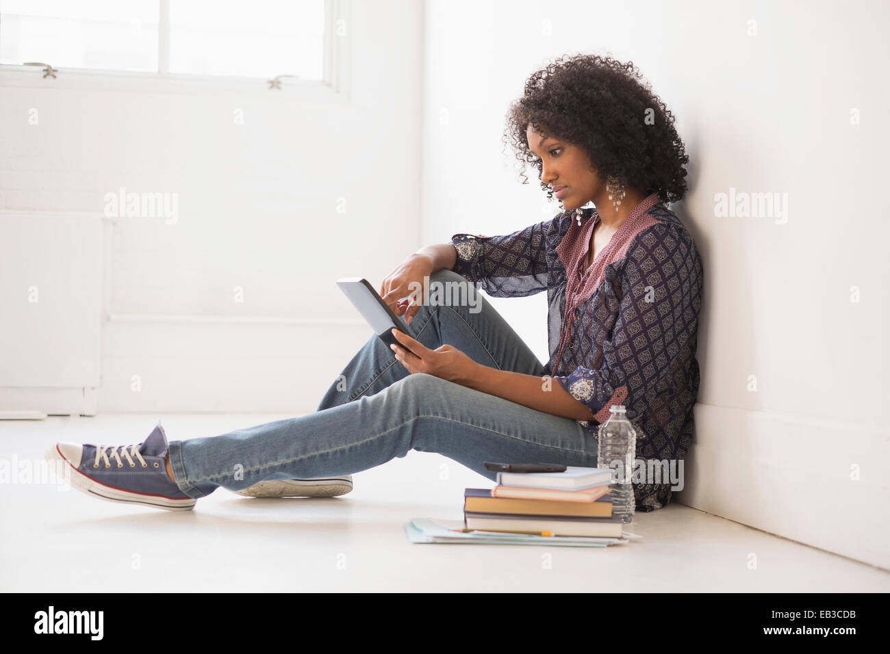 Mixed Race college student sitting on floor Banque D'Images