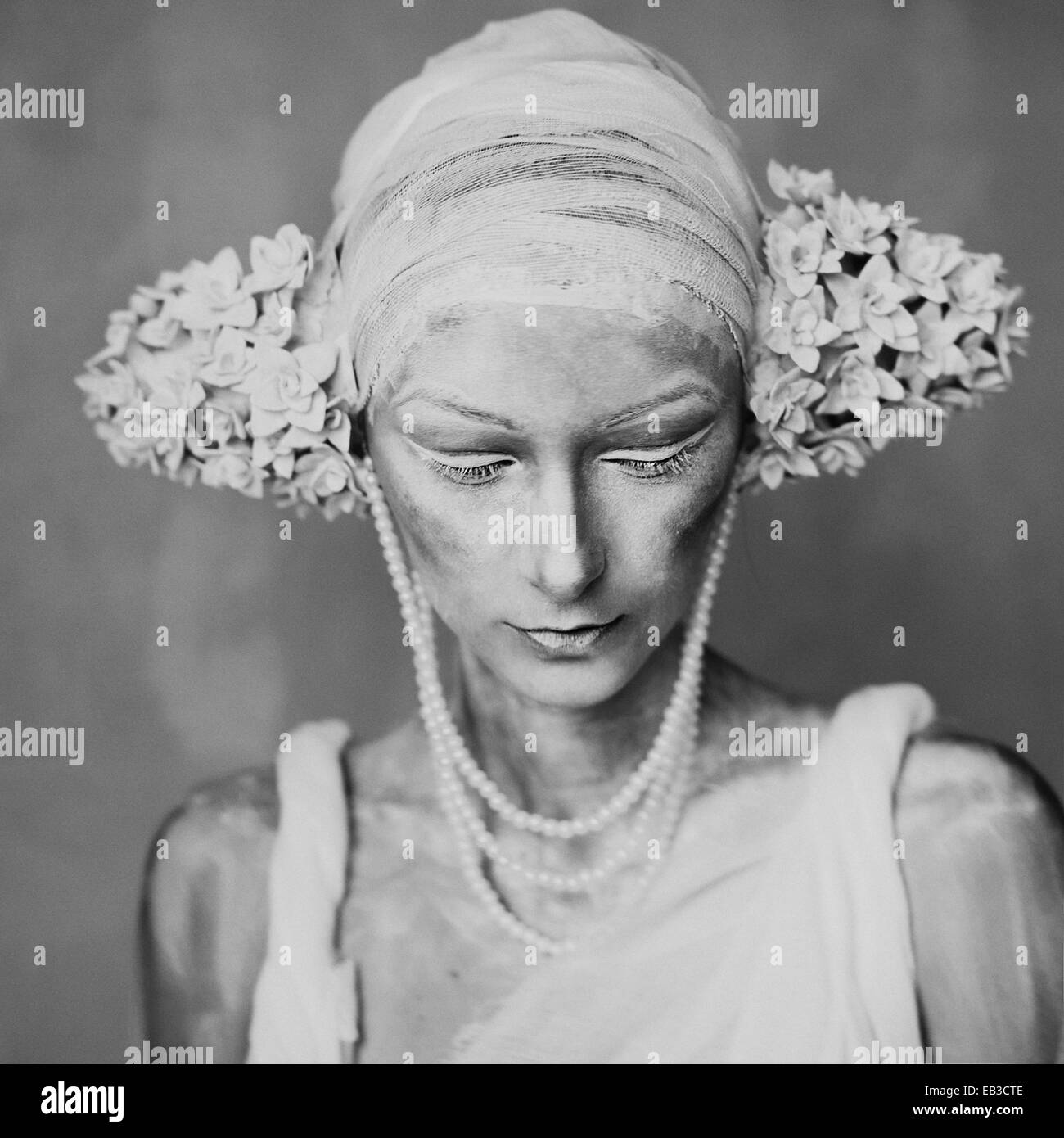 Portrait of young woman wearing composent, greasepaint, perles, et décorations de l'oreille de l'inflorescence ressemblant Banque D'Images