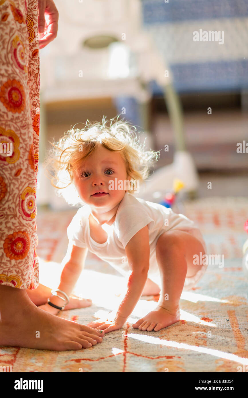 Caucasian baby boy crouching par pieds de mère Banque D'Images