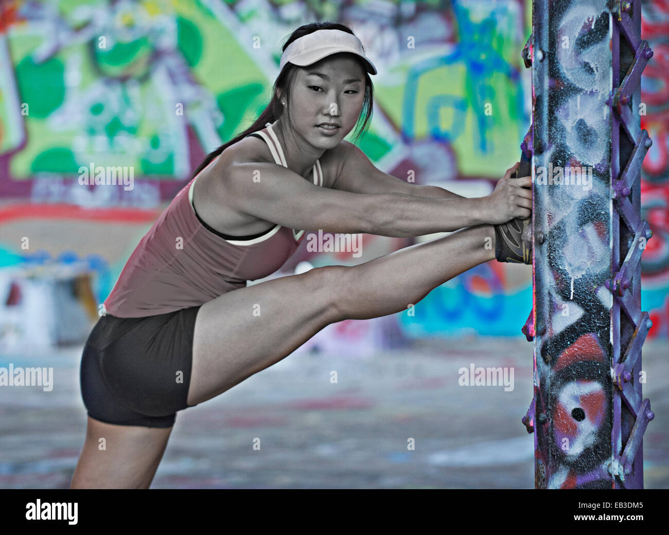 Runner coréen s'étendant sur colonne avec graffiti Banque D'Images
