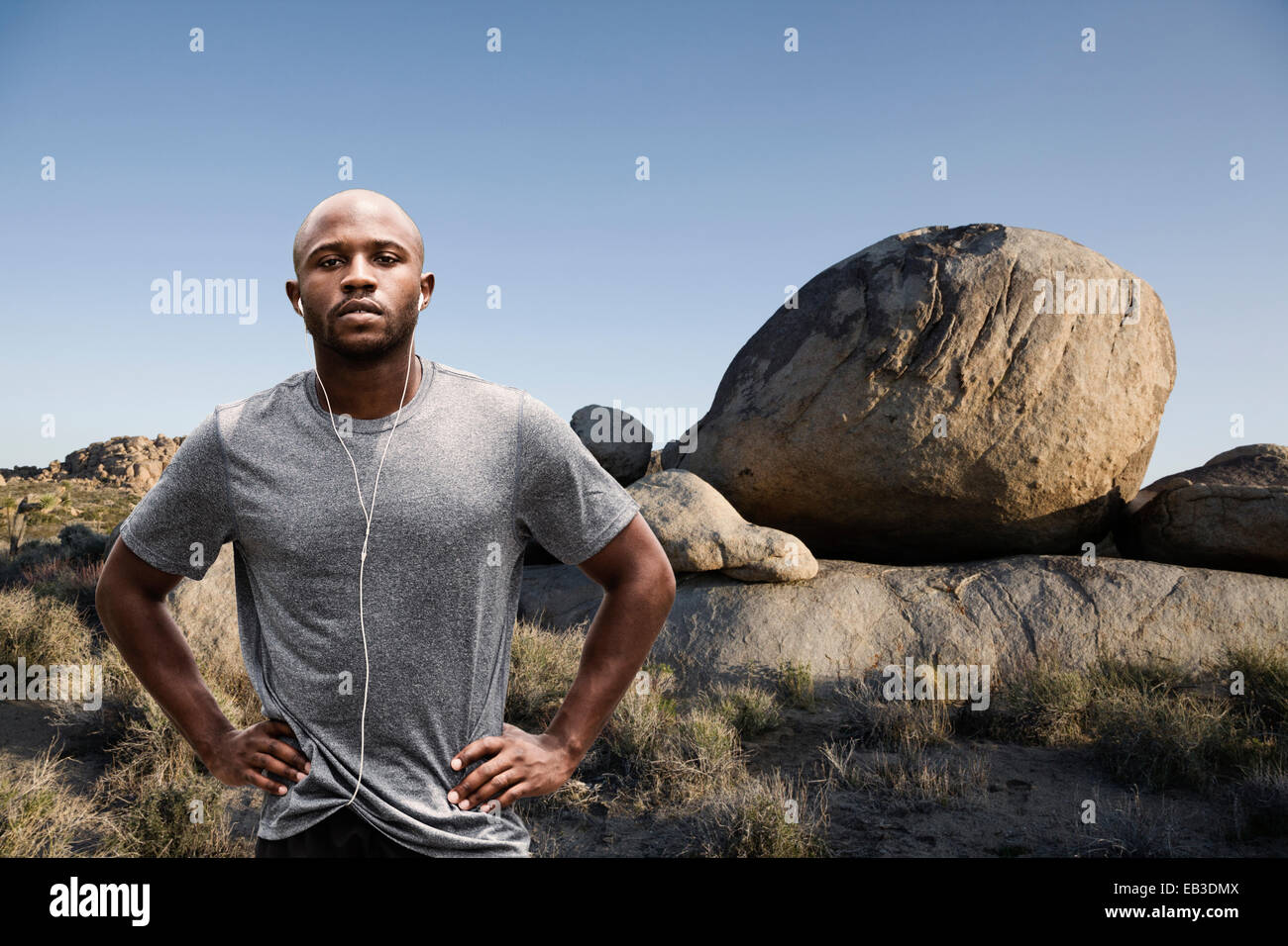 Black runner standing in rocky landscape à distance Banque D'Images