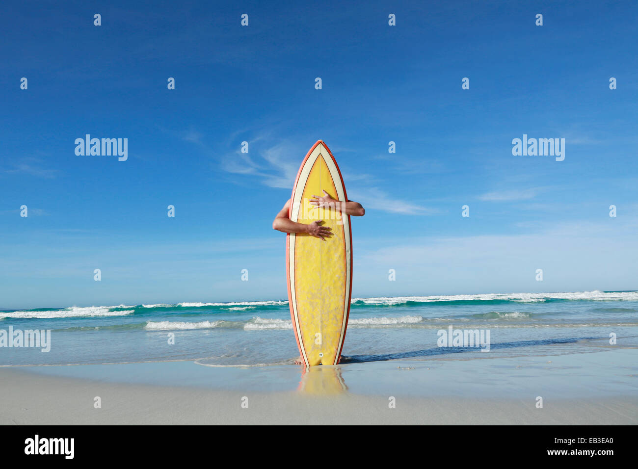 L'Australie, Man embracing surf verticalement sur beach Banque D'Images