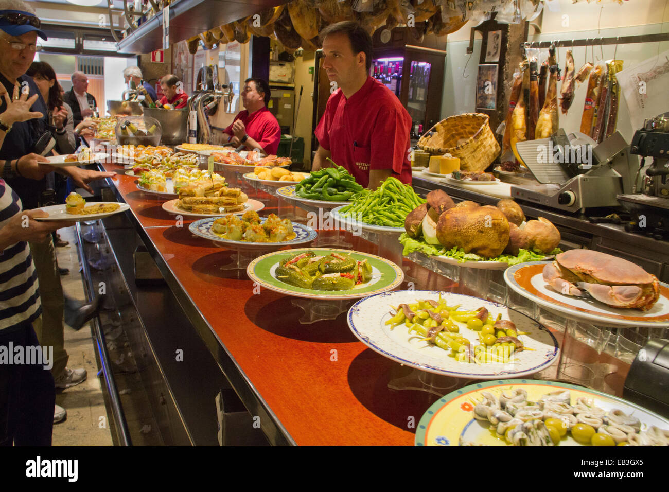 Des plaques (tapas pintxos en basque) sur le bar et les clients commander ce qu'ils veulent, San Sebastian, Espagne Banque D'Images