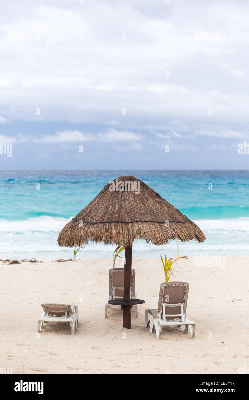 Parasol et lits de plage des Caraïbes par temps nuageux, Cancun, Mexique Banque D'Images Parasol et lits de plage des Caraïbes par temps nuageux, Cancun, Mexique Banque D'Images