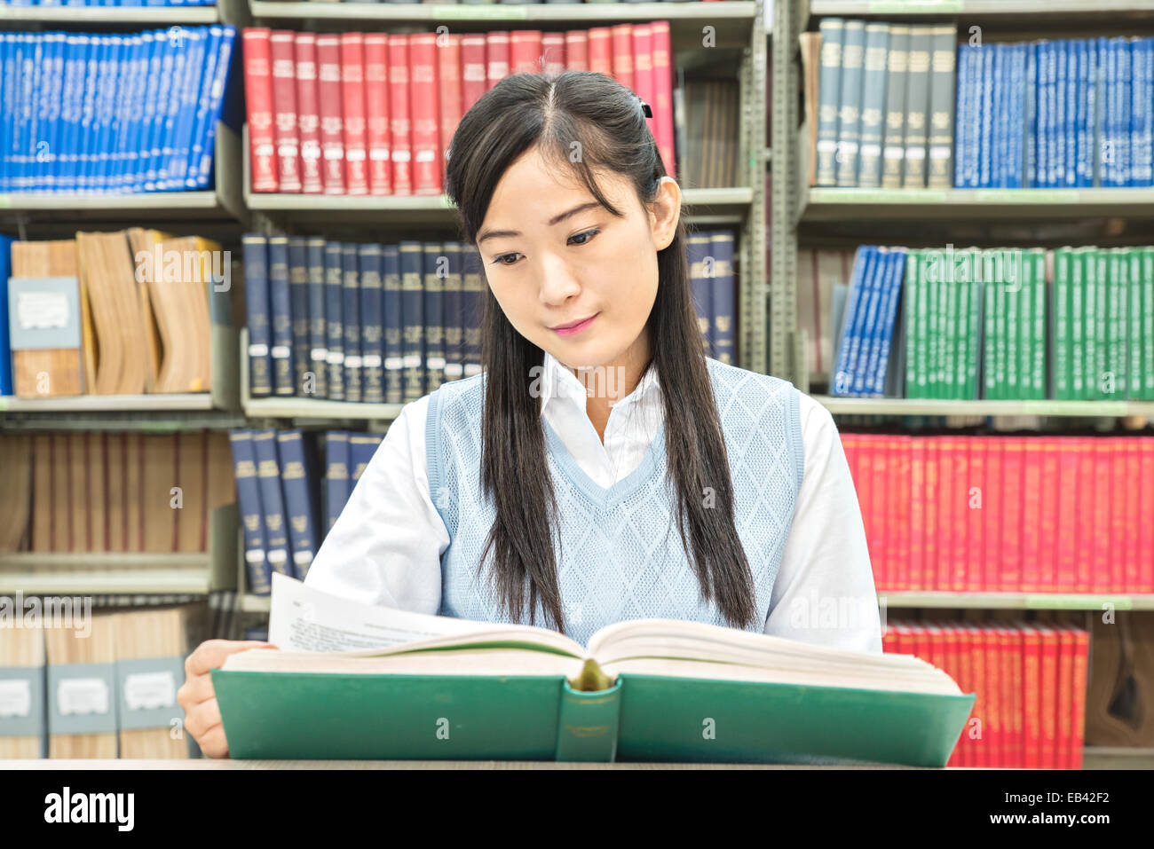 Étudiant asiatique avec livre ouvert lecture in college library Banque D'Images