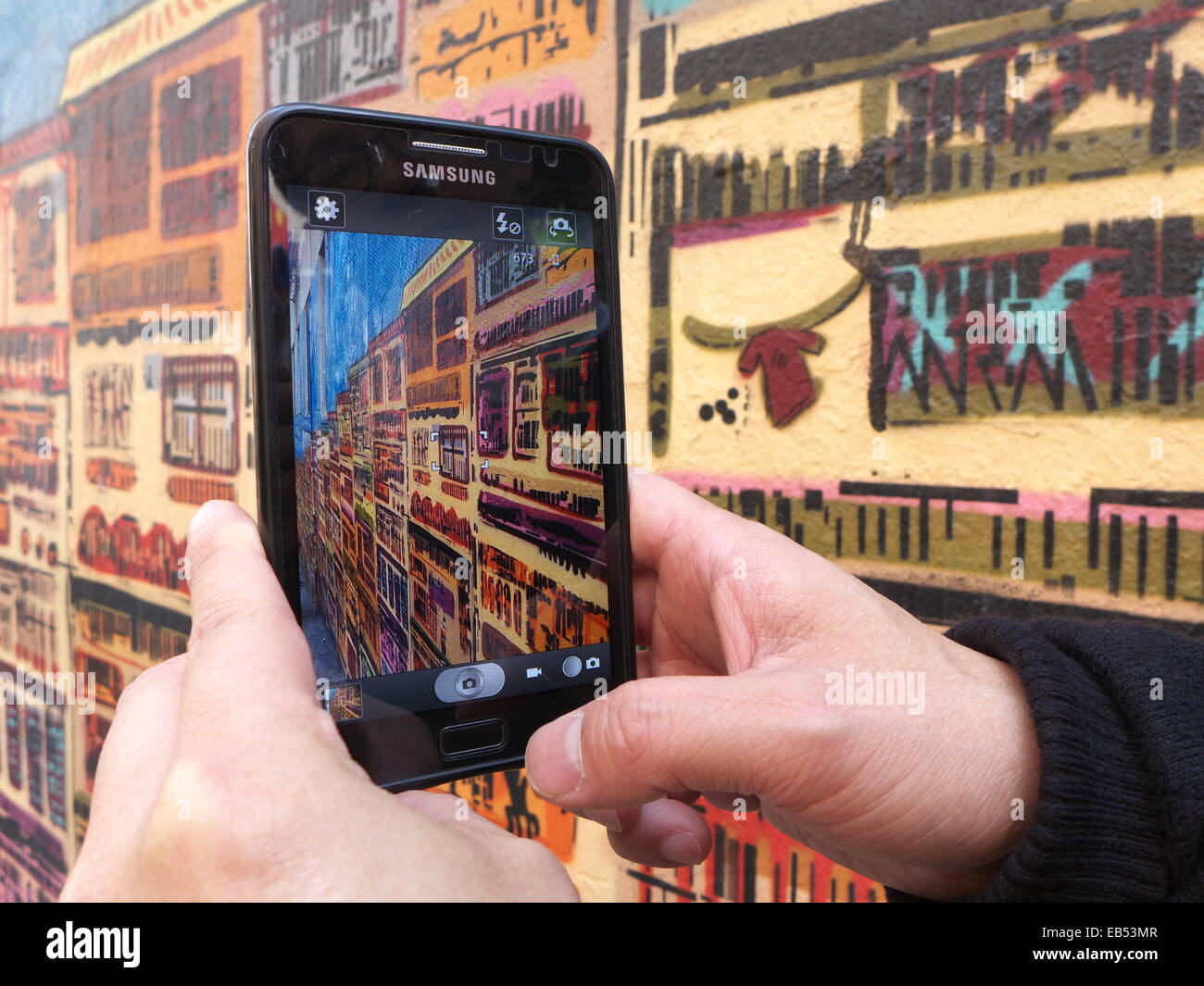 Chine Hong Kong man with smartphone Samsung graffiti peinture murale Banque D'Images