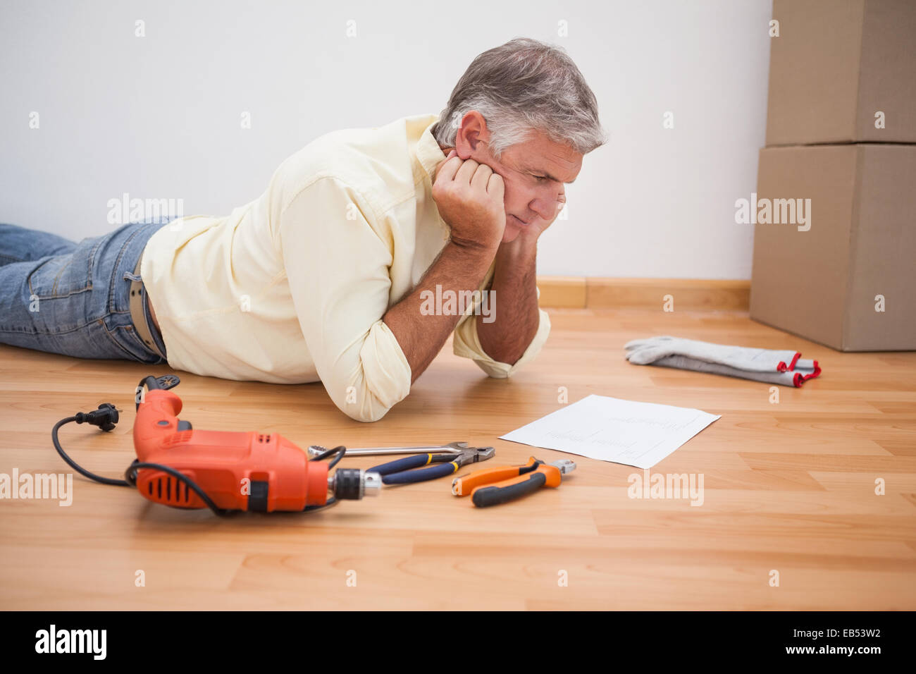 Man lying on floor instructions de l'outil de lecture Banque D'Images