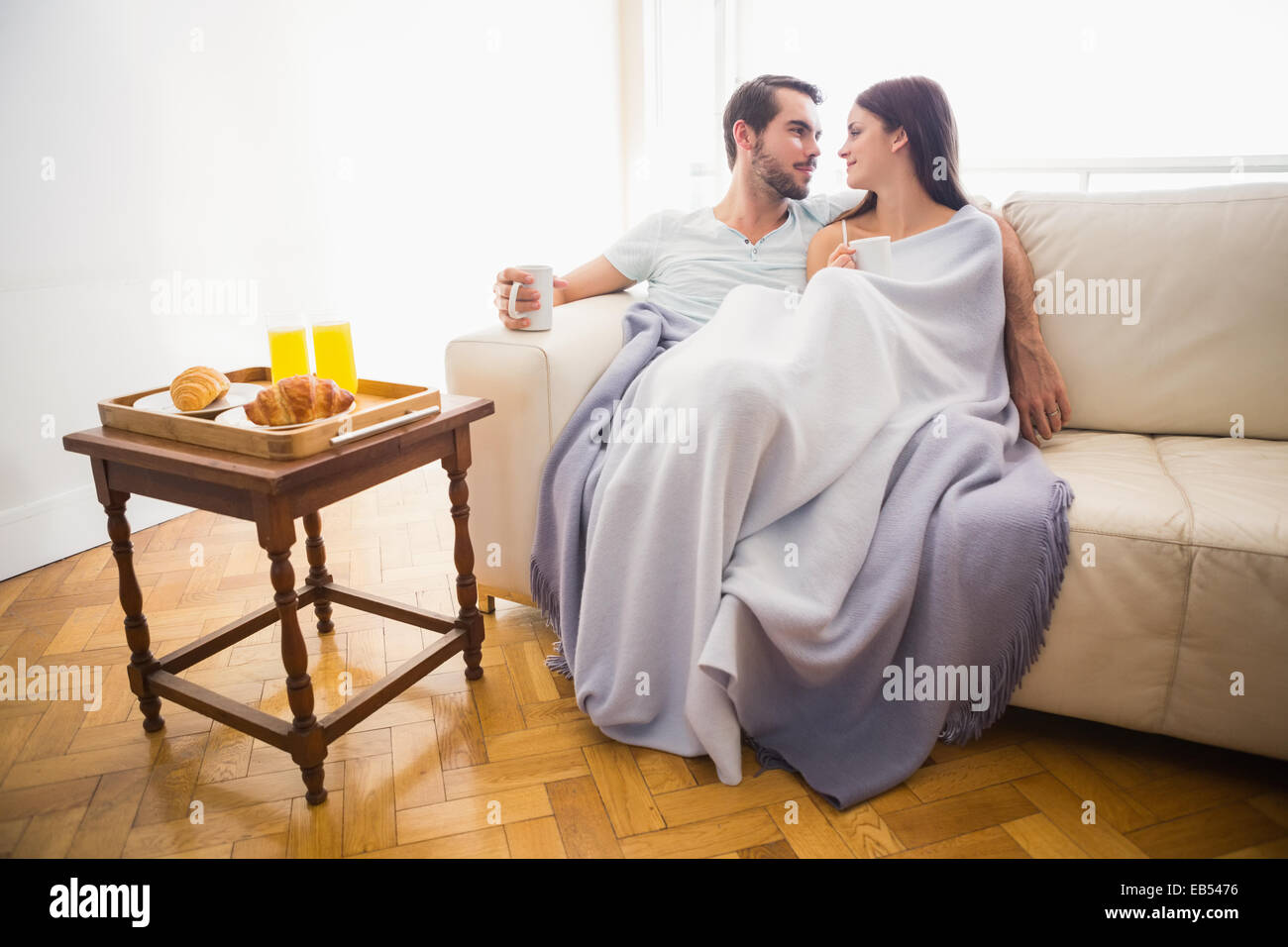 Cute couple relaxing on couch sous couverture Banque D'Images