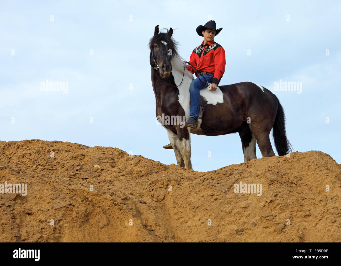 Dans l'homme vêtements cowboy rides bareback sur un cheval repéré sur une colline de sable Banque D'Images