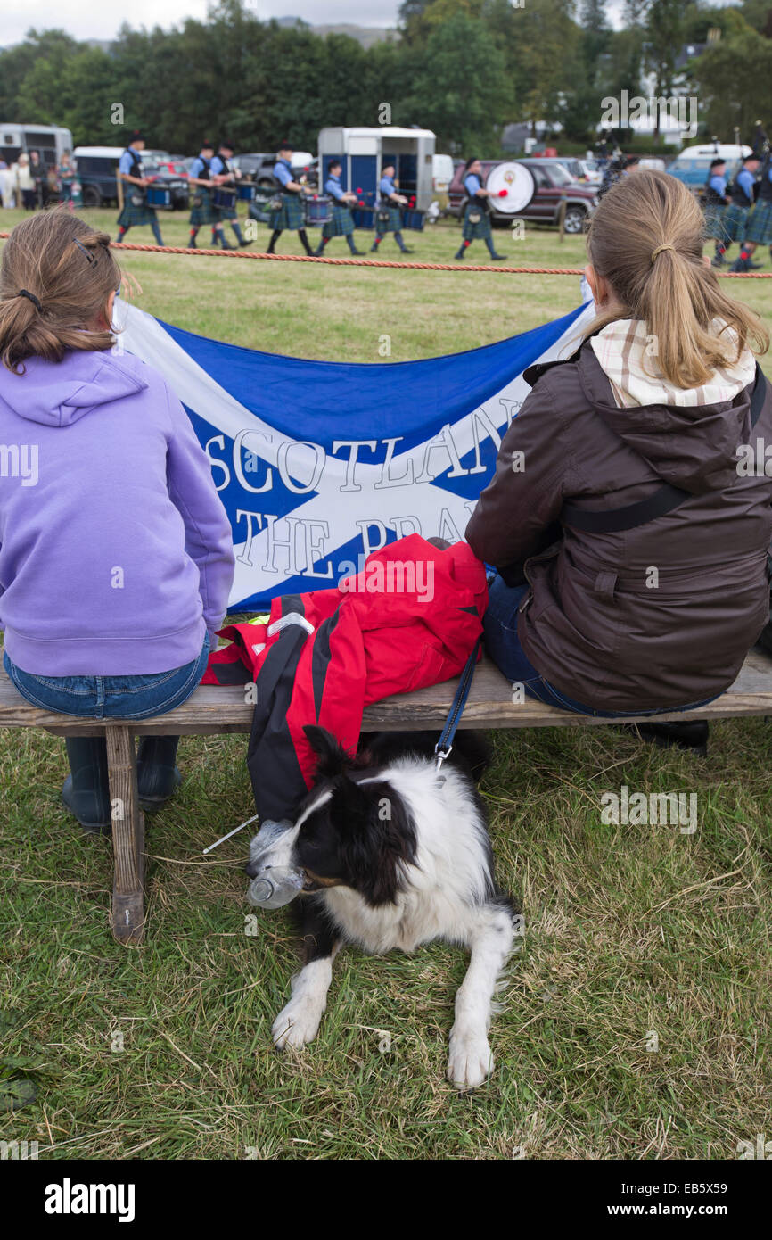Deux jeunes filles et leur chien regardant un pipe band écossais à l'Dalmally Agricultural Society Show à Dalmally, en Écosse. Banque D'Images