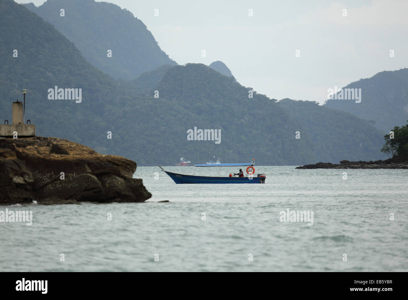 Un bateau de pêche par un îlot au large de Pulau Langkawi, Malaisie. L'archipel de Langkawi se trouve dans le détroit de Malacca. Banque D'Images