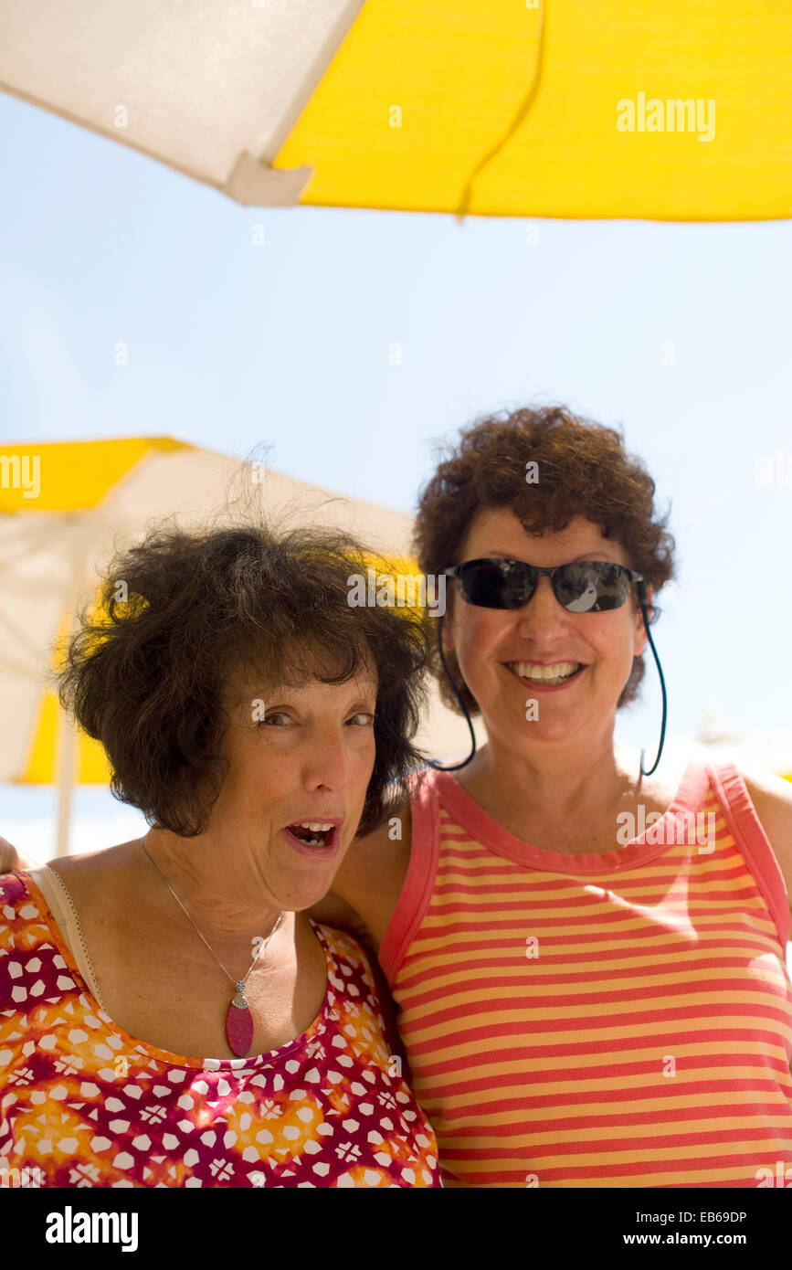 Deux femmes âgées, à la retraite depuis longtemps de vieux amis heureux en Riant et blaguant beach Banque D'Images