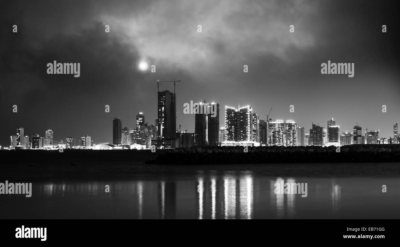 Photo en noir et blanc. Nuit sur la ville moderne avec la lune brillante. Manama, la capitale de Bahreïn, au Moyen-Orient Banque D'Images