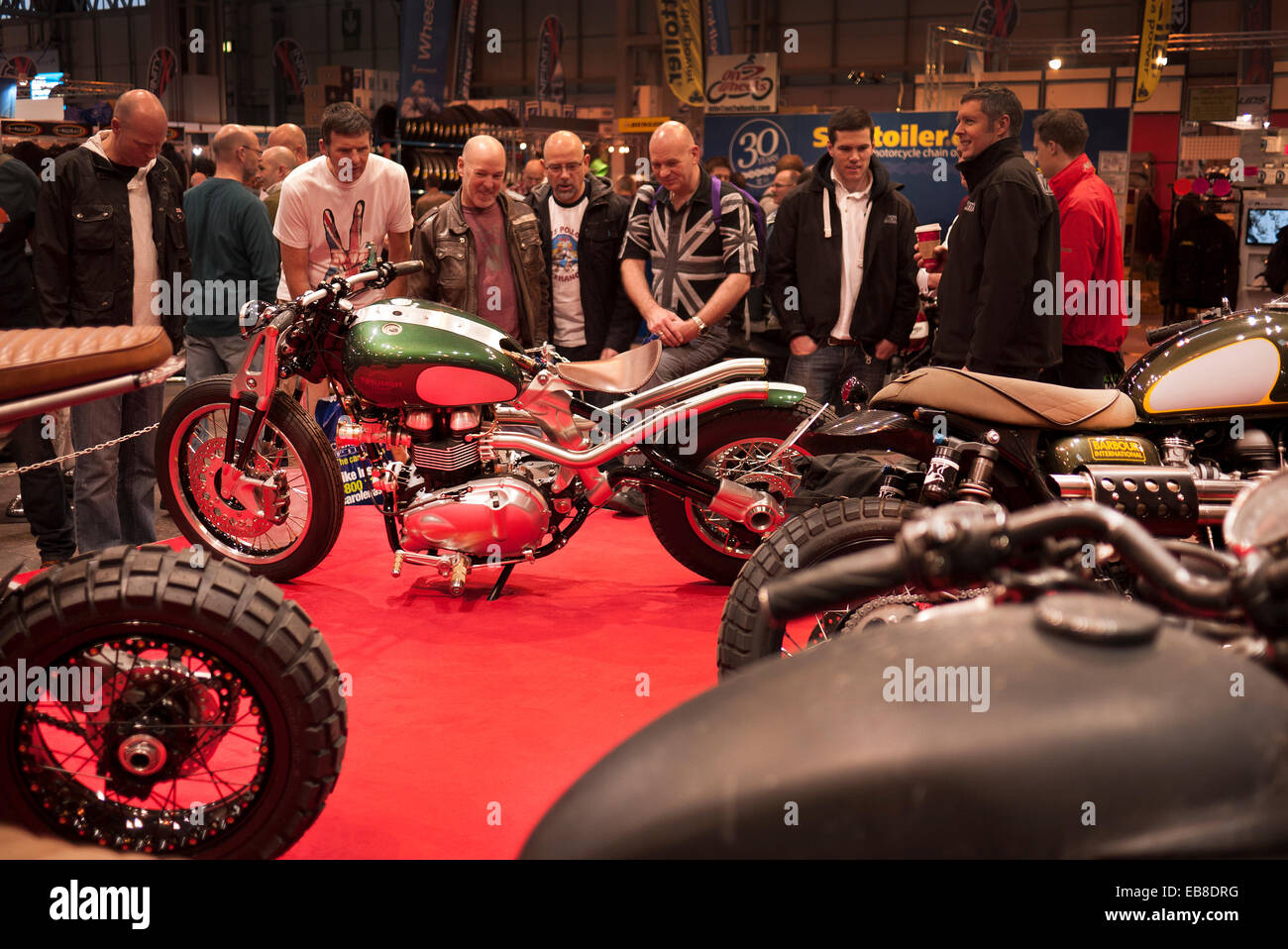 Les visiteurs de la Live show moto à Birmingham, NEC, jeter un oeil à une moto custom Triumph. Banque D'Images