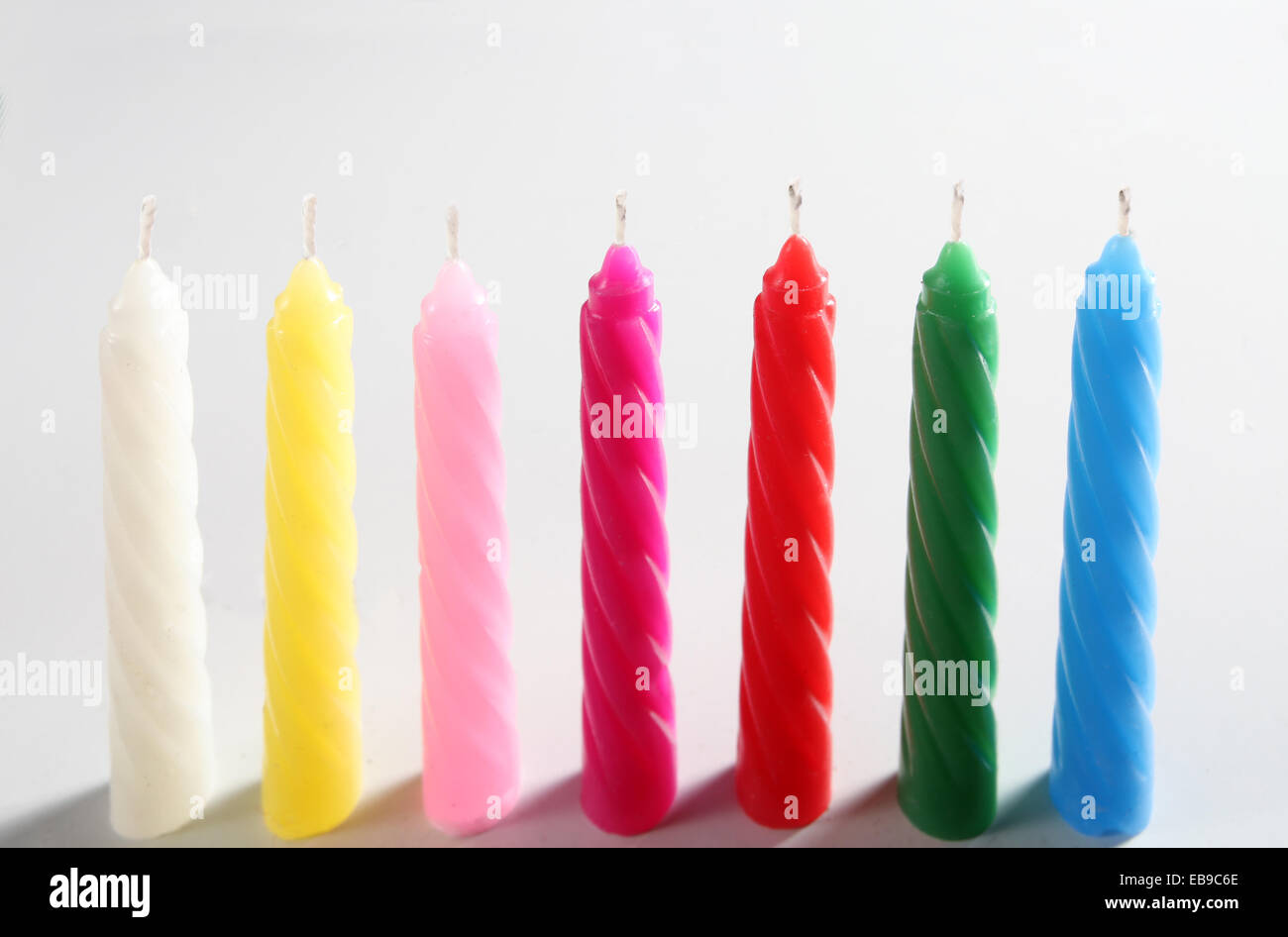 Sept bougies colorés sur fond blanc Banque D'Images