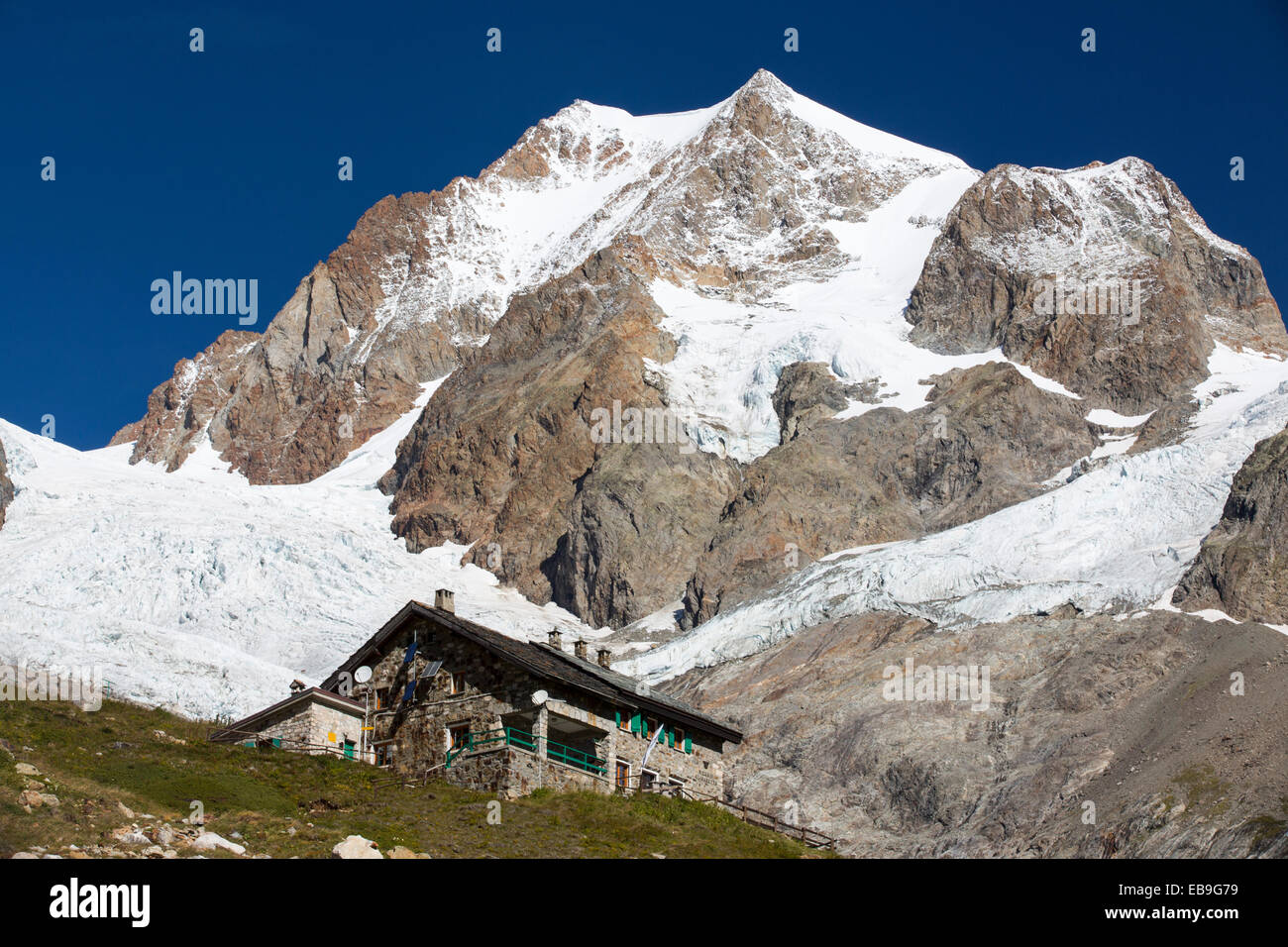 Le Refuge E Soldiel au-dessous de l'Aiguille de Tre La tete dans les Alpes italiennes sur le Tour du Mont Blanc, avec le recul des glaciers de rapidement Glacier De La Lex Blanche et des glaciers du Petit Mont Blanc. Banque D'Images