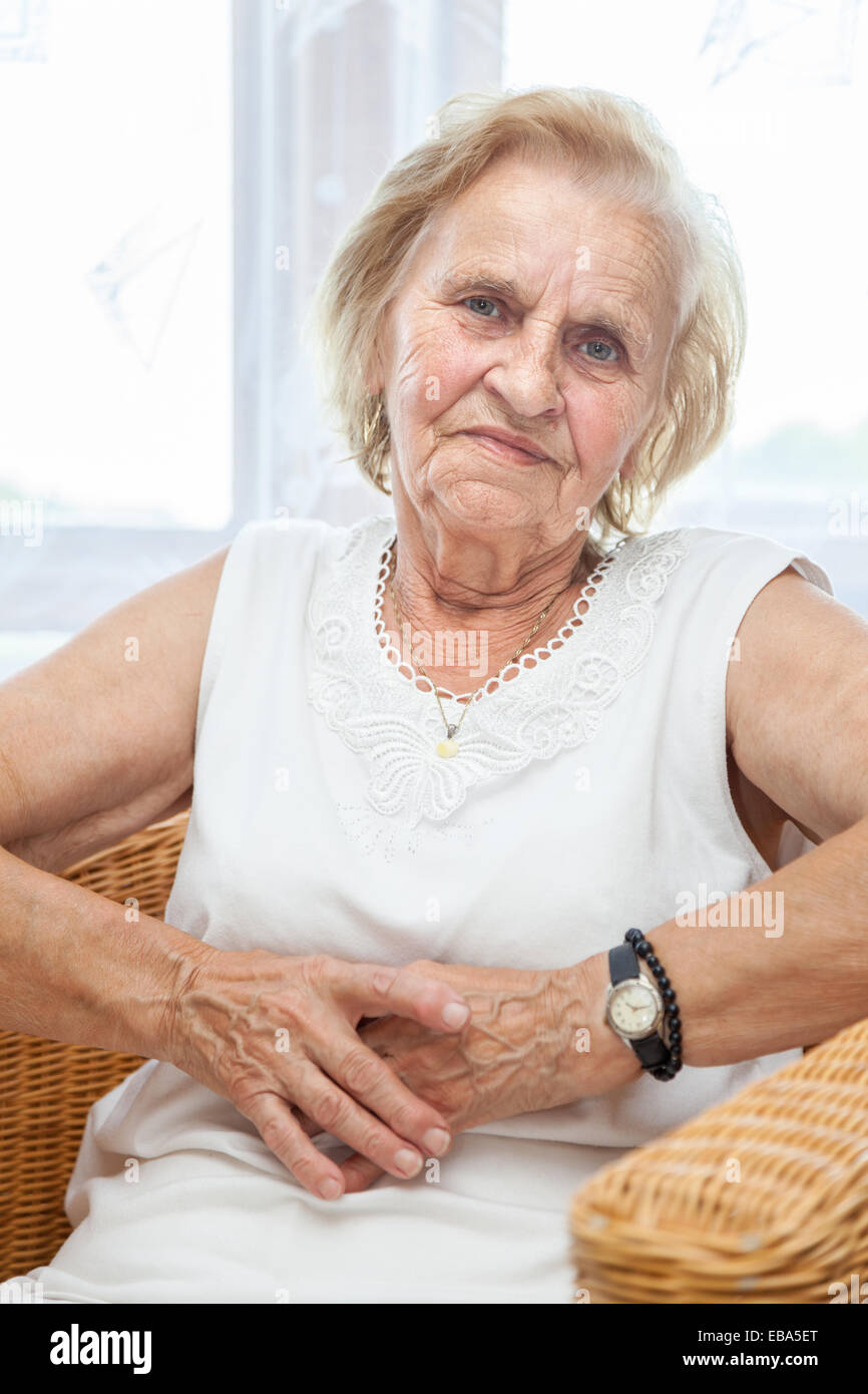 Portrait d'une vieille dame dans son 70s'asseoir sur une chaise Banque D'Images