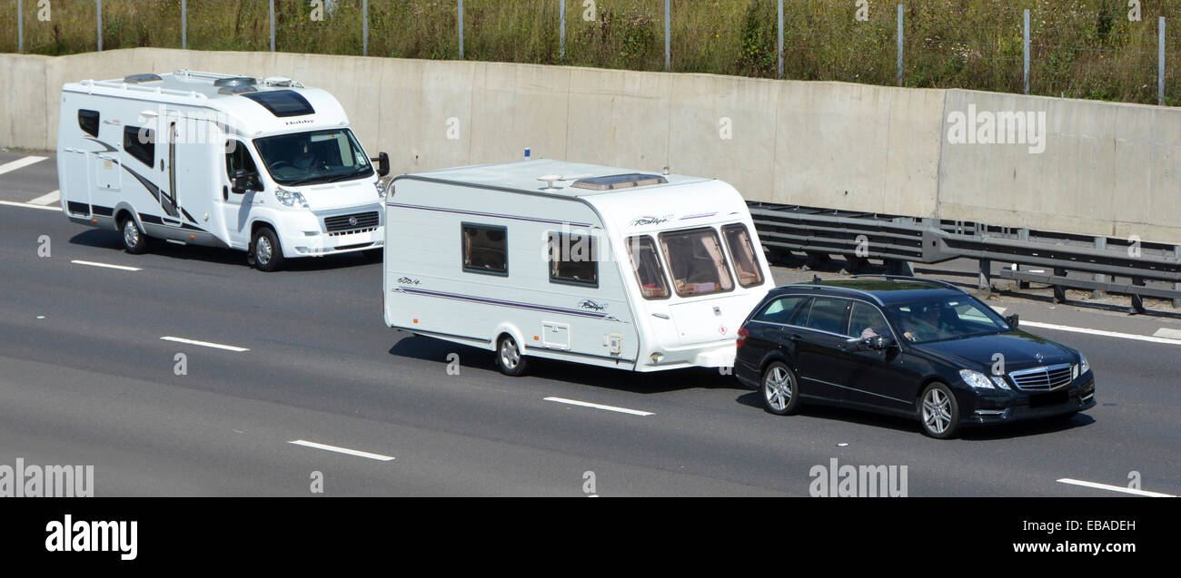 Deux vacances d'été transport options de voyage et de camping voiture remorquage caravane blanche dépassement camping camping camping-car camping-cars van home conduite le long de l'autoroute Angleterre Royaume-Uni Banque D'Images