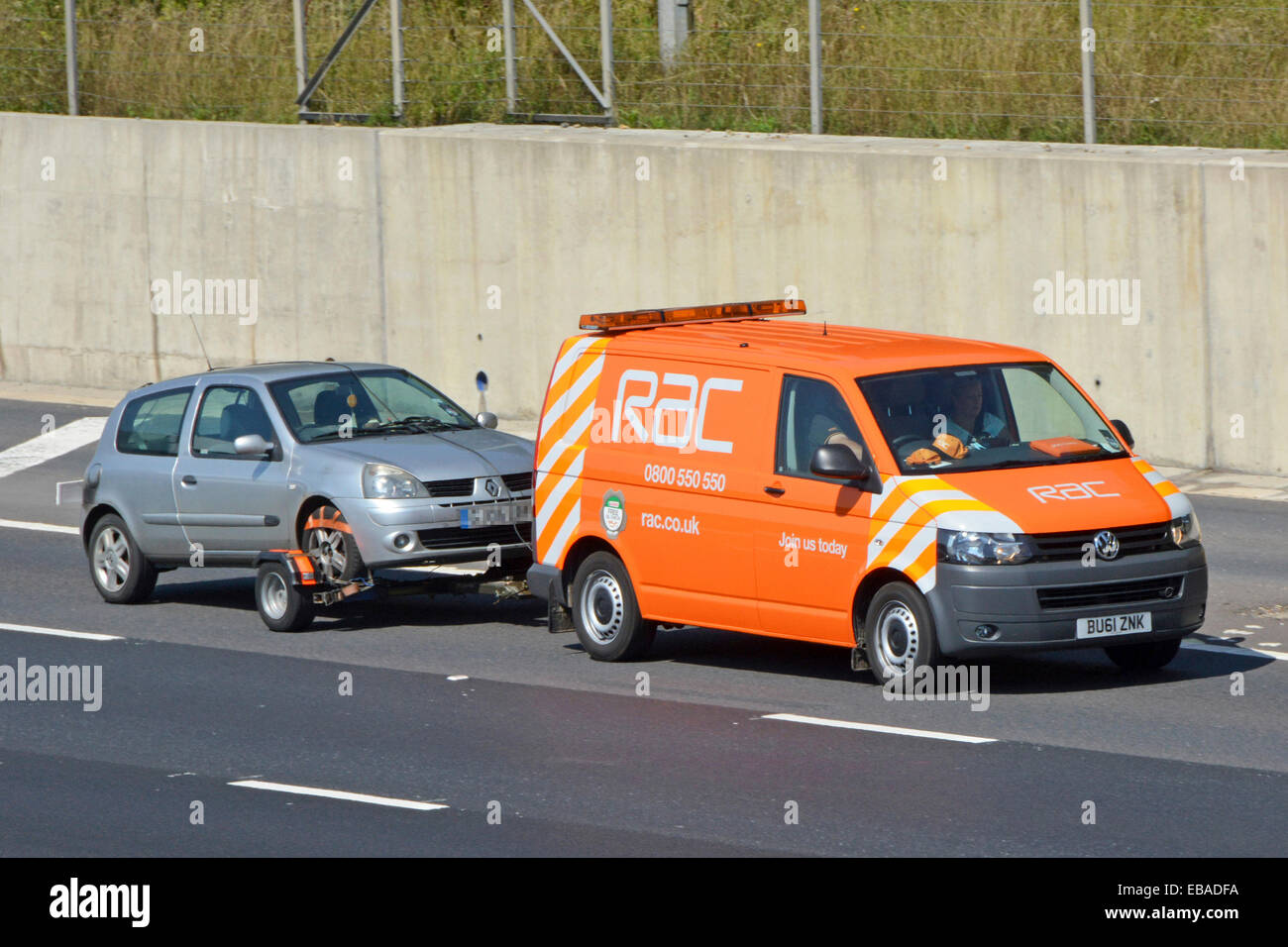 Vue latérale et avant du logo de la marque sur le RAC VW Volkswagen Panne de la fourgonnette d'affaires remorquage conducteur et passager panne Renault Voiture sur l'autoroute britannique en Angleterre Banque D'Images