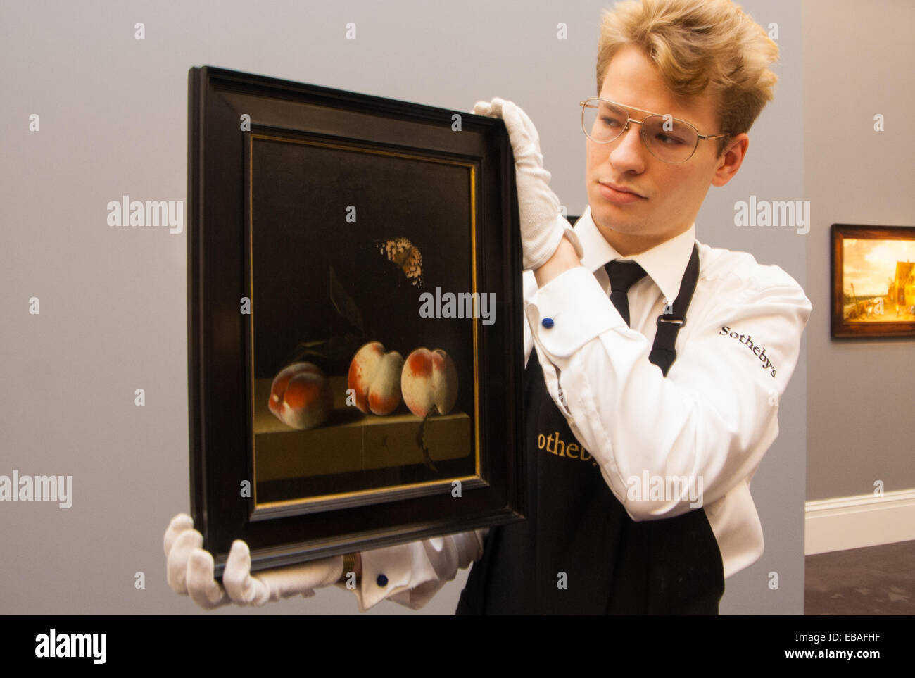 Sotheby's Londres, Royaume-Uni. 28 Nov, 2014. Sotheby's tenir un essai pour leur 3e décembre vente d'ancien maître et peintures britanniques à leur Bond Street gallery. L'exposition est présentée du 29 novembre au 3 décembre. Photo : Sotheby's Gallery Un technicien prépare pour accrocher les trois pêches Adriaen Coorte sur un rebord en pierre avec un papillon amiral rouge, considéré comme l'une des plus belles œuvres de l'artiste, prévu pour aller chercher entre £3 millions de dollars aux enchères. Crédit : Paul Davey/Alamy Live News Banque D'Images
