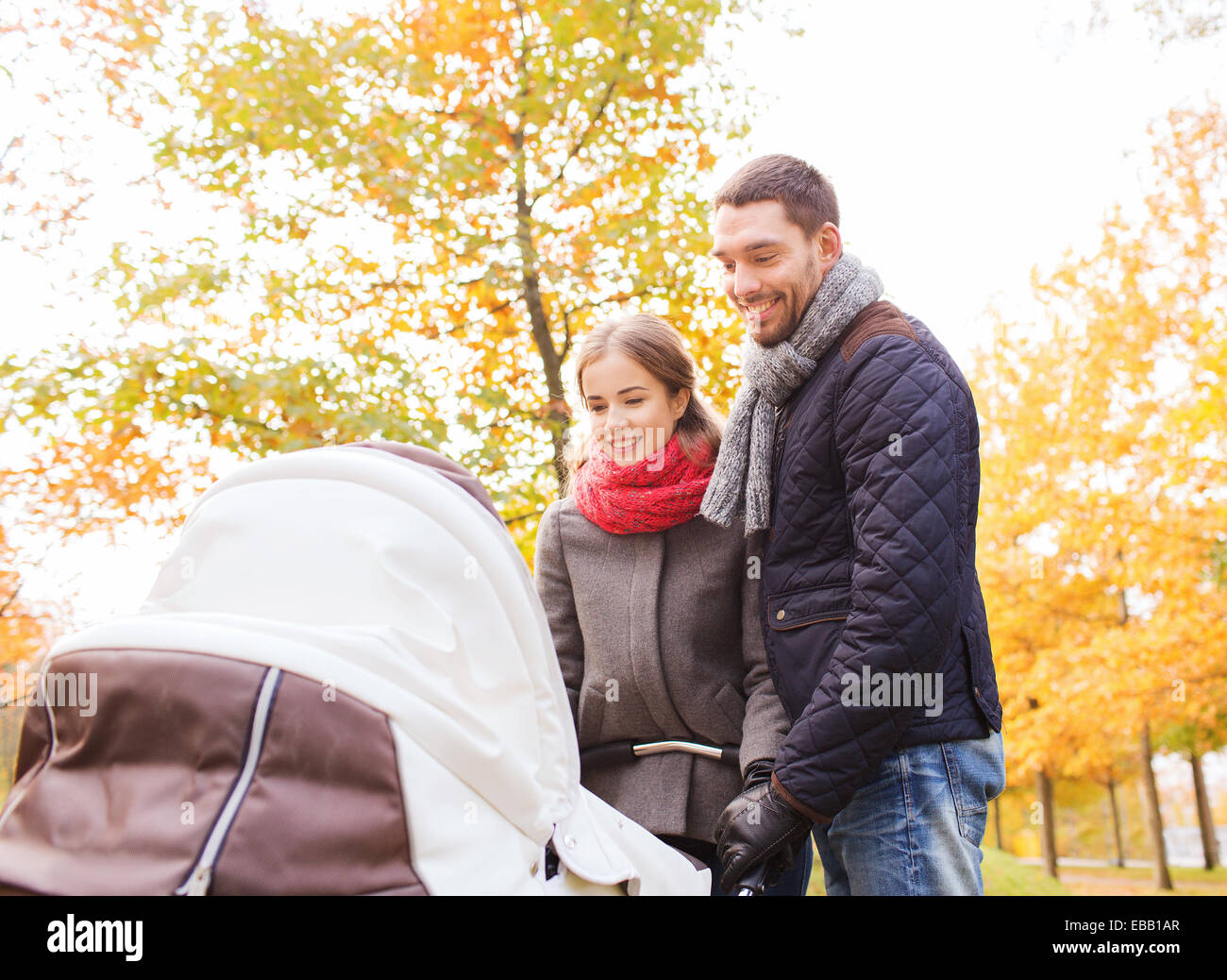 Smiling couple avec bébé la pram in autumn park Banque D'Images