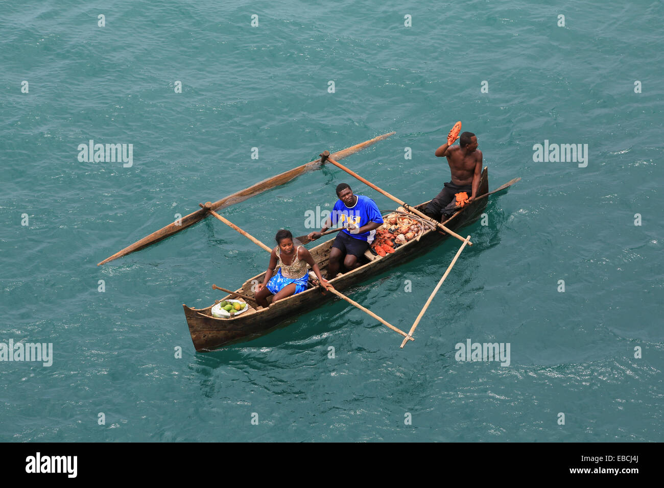 Des villageois dans un outrigger canoë sont offrant des biens à la vente aux passagers de navires de croisière à Nosy Be, Madagascar. Banque D'Images
