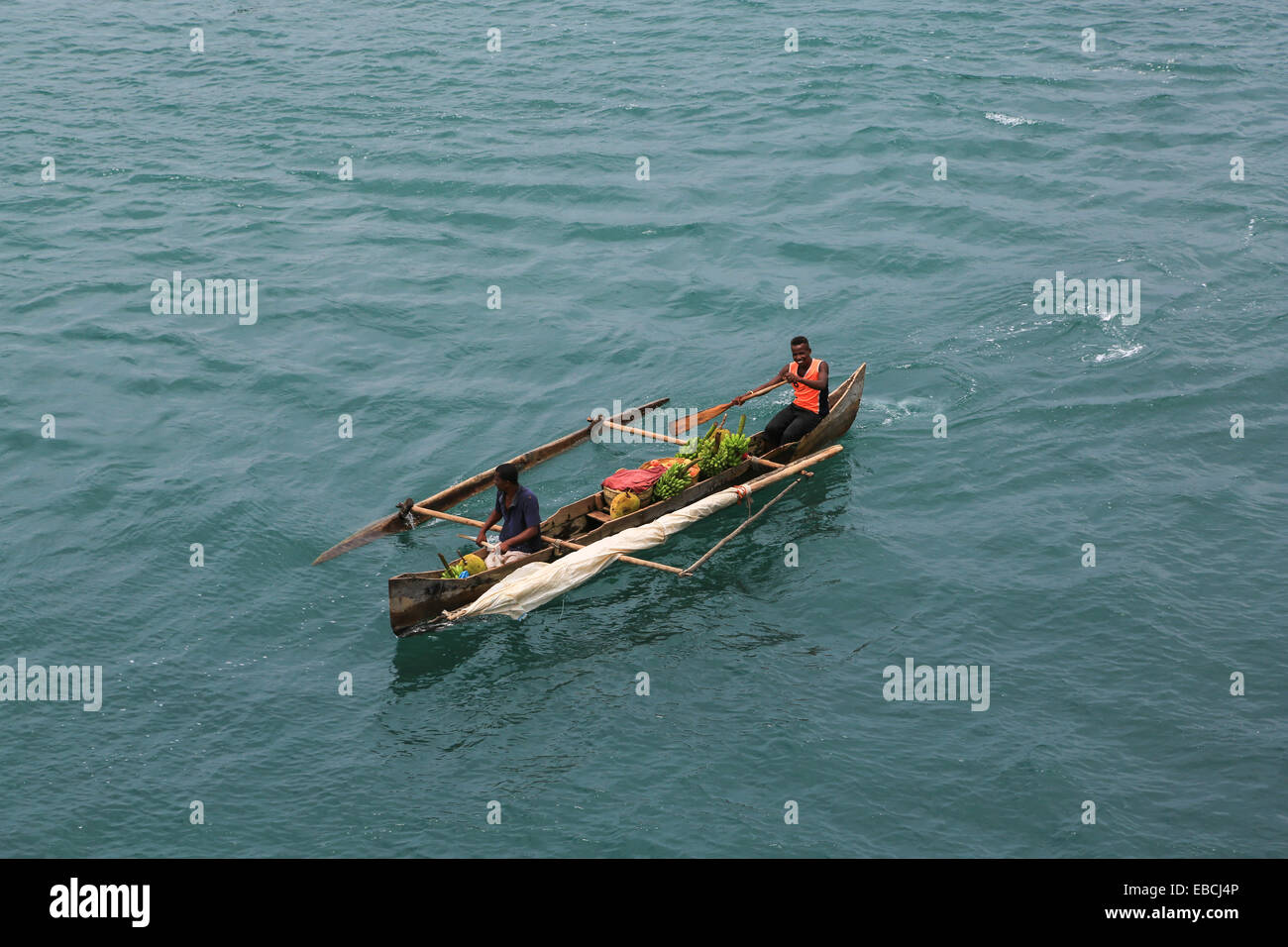 Des villageois dans un outrigger canoë sont offrant des biens à la vente aux passagers de navires de croisière à Nosy Be, Madagascar. Banque D'Images