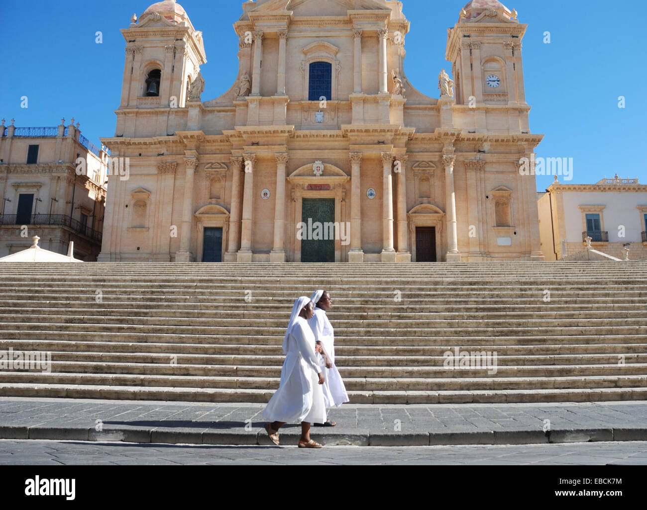 Deux religieuses marchant devant une église de Noto, en Sicile, Italie. Banque D'Images