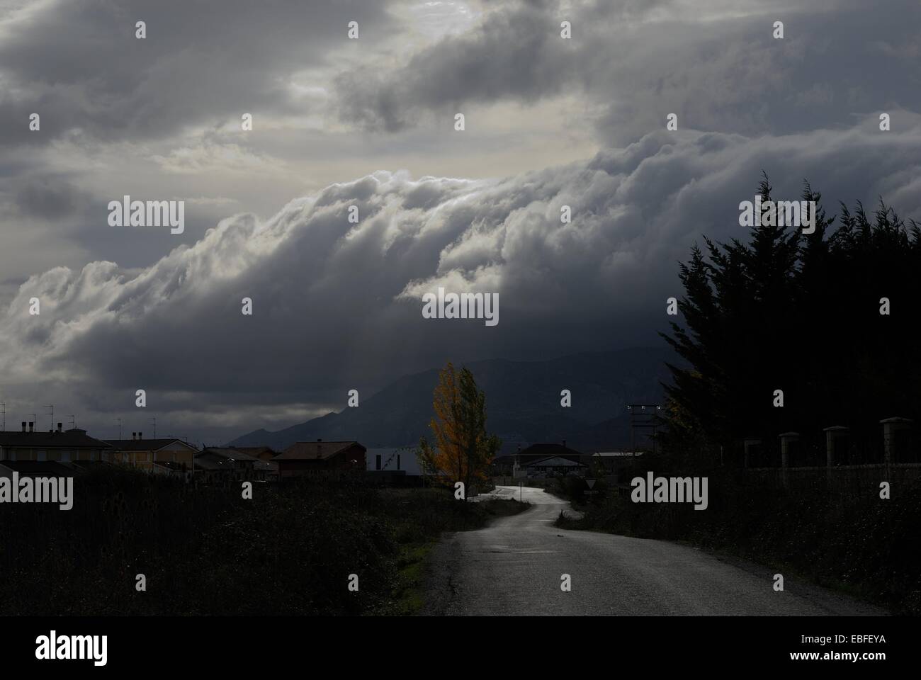 Paysage composé d'une route, arbres et nuages orageux Banque D'Images