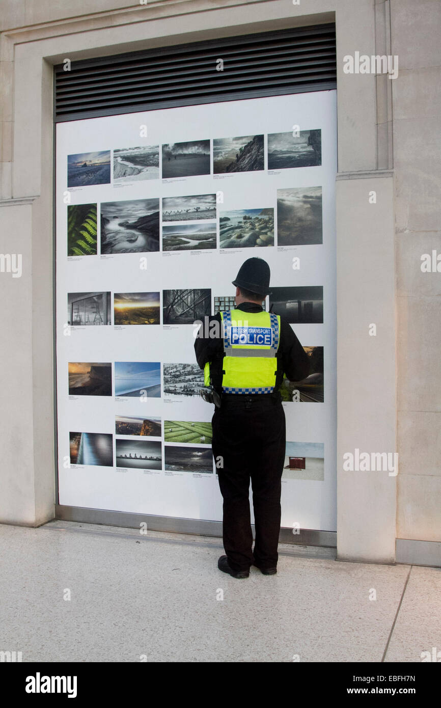 London UK. Le 30 novembre 2014. un agent de la police britannique des Transports prend du temps pour voir une exposition photographique à Waterloo Station Crédit : amer ghazzal/Alamy Live News Banque D'Images