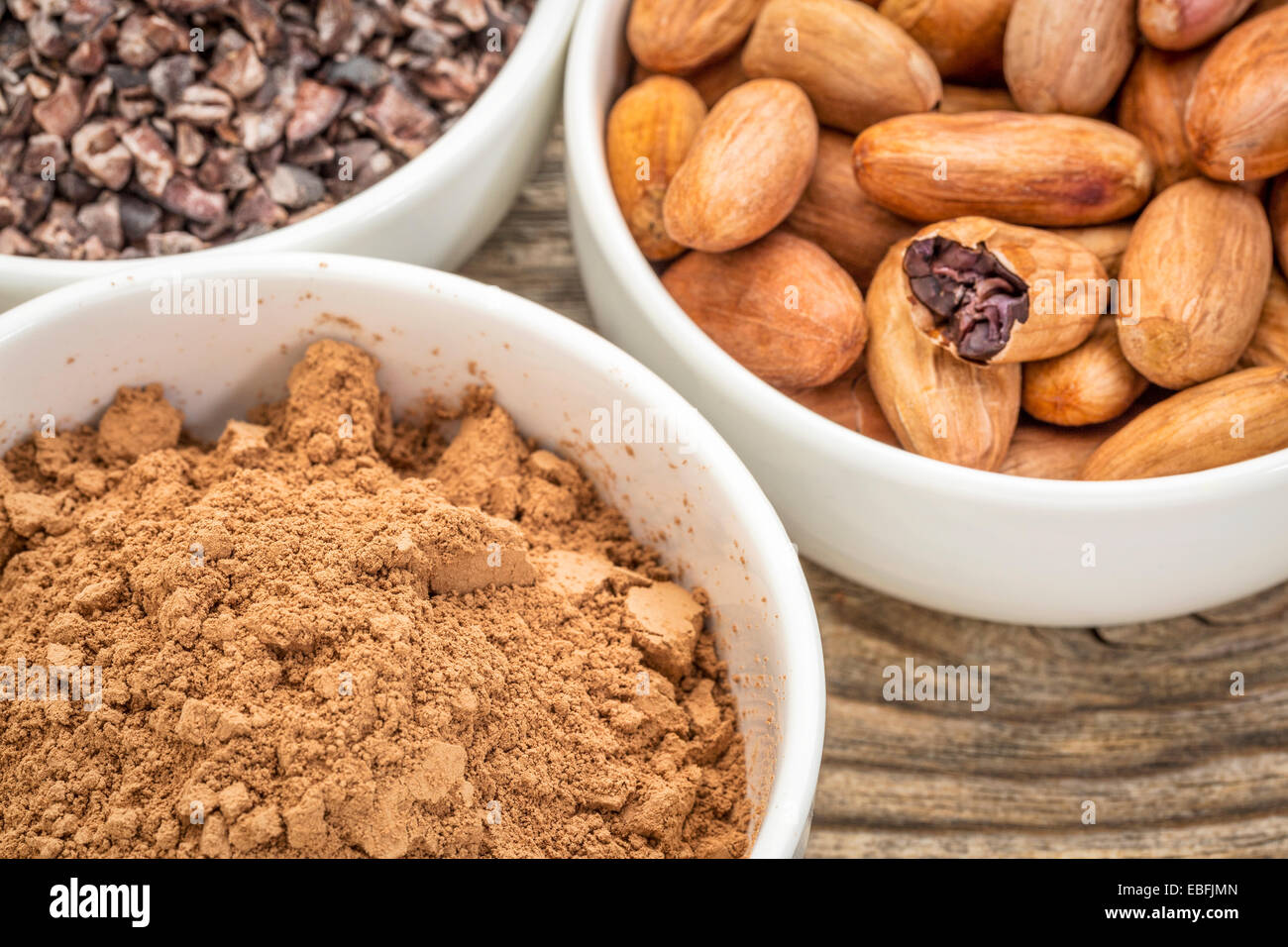 Les fèves de cacao, plumes et en poudre en céramique blanche contre le bois à grain fin Banque D'Images