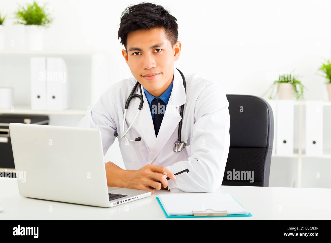 Jeune médecin travaillant avec laptop in office Banque D'Images