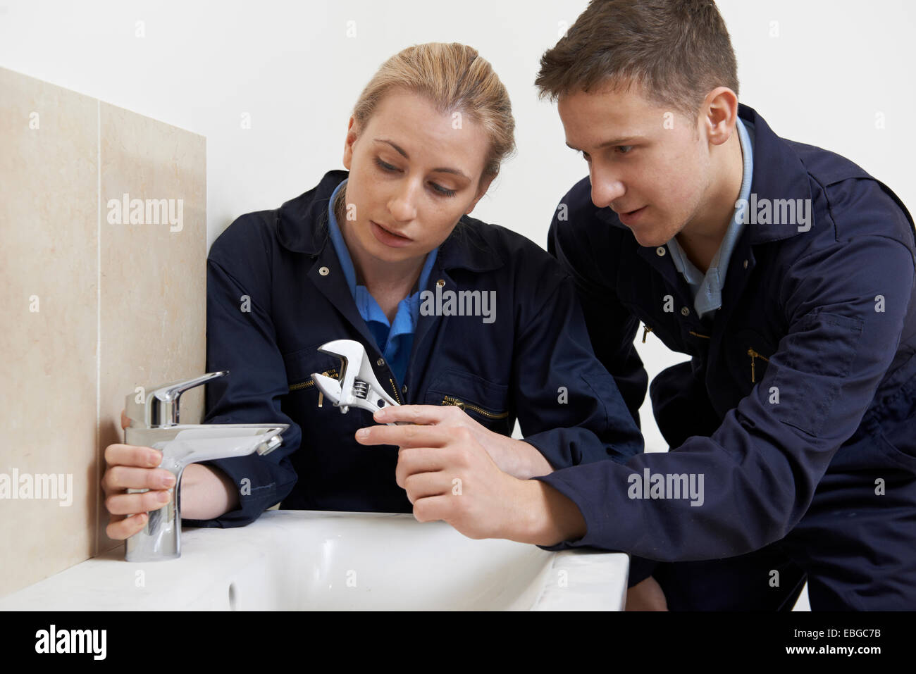Stagiaire féminine plombier travaillant sur le robinet dans la salle de bains Banque D'Images