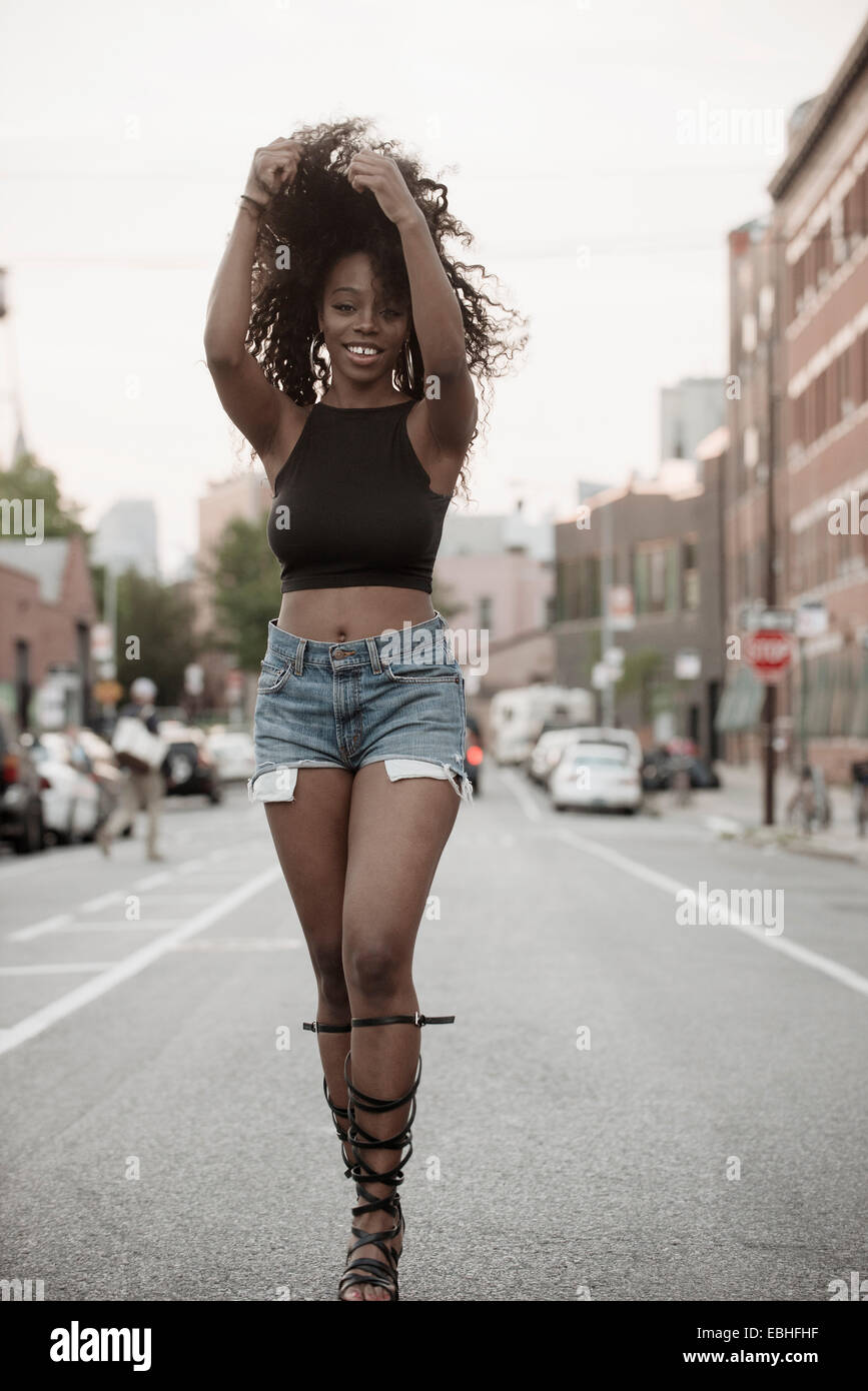 Young woman standing in street avec les mains dans les cheveux Banque D'Images