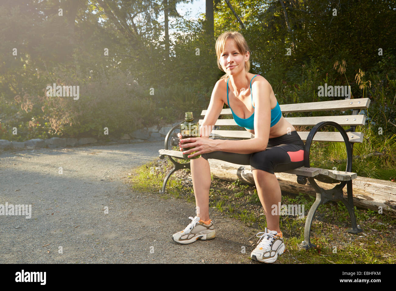 Portrait of smiling female runner Taking a break on park bench Banque D'Images