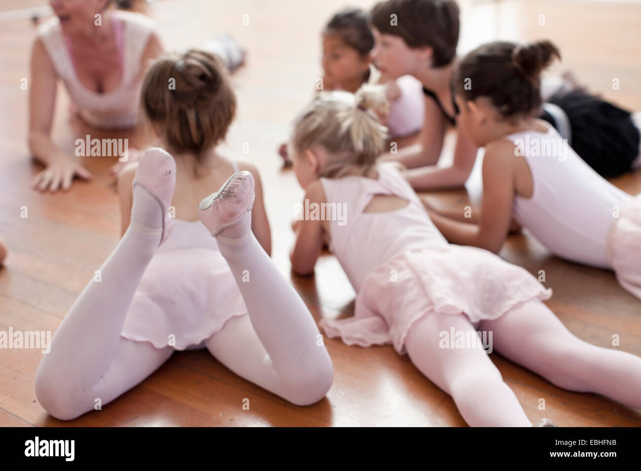 Children lying on floor practicing ballet in ballet school Banque D'Images
