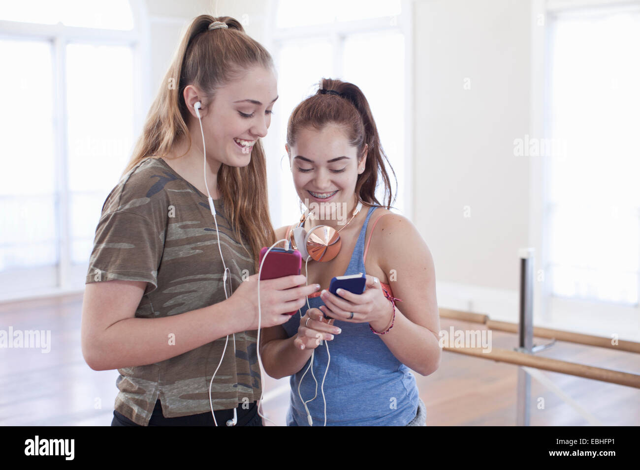 Deux adolescentes listening to earphones in ballet school Banque D'Images