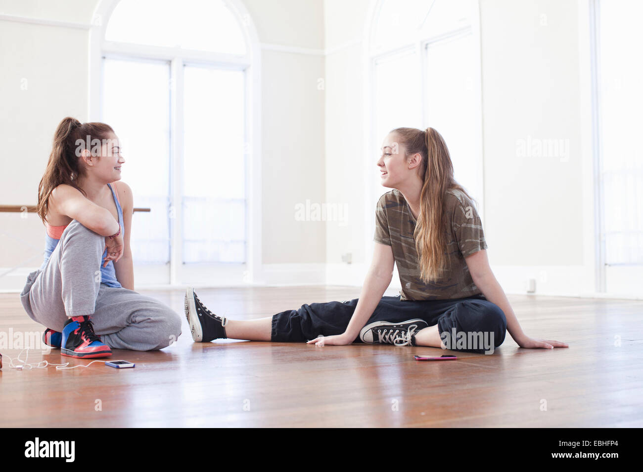 Deux adolescentes sitting on floor chatting in ballet school Banque D'Images