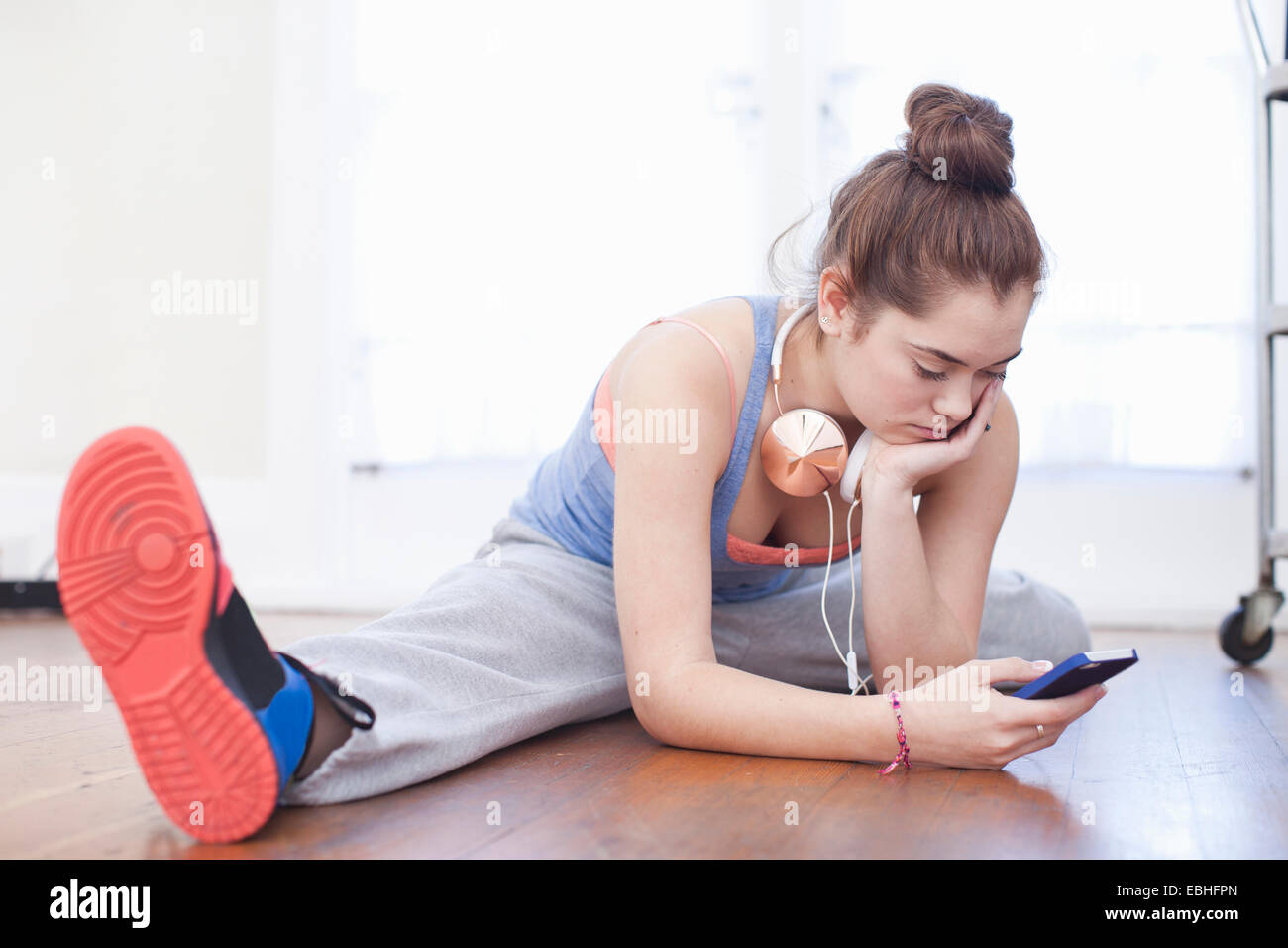 Teenage girl le réchauffage et looking at smartphone dans ballet school Banque D'Images