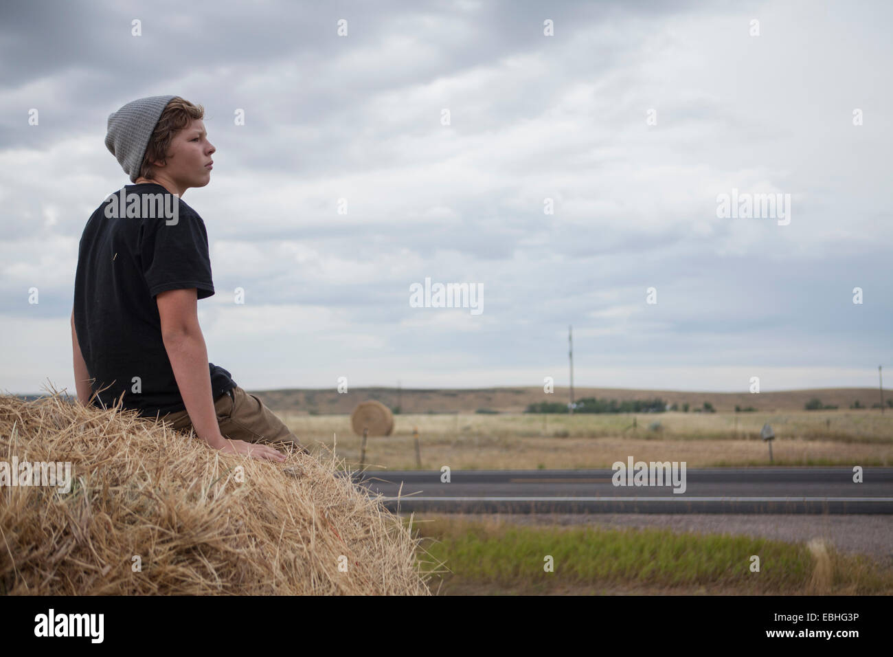 Teenage boy sitting on haystack, South Dakota, USA Banque D'Images