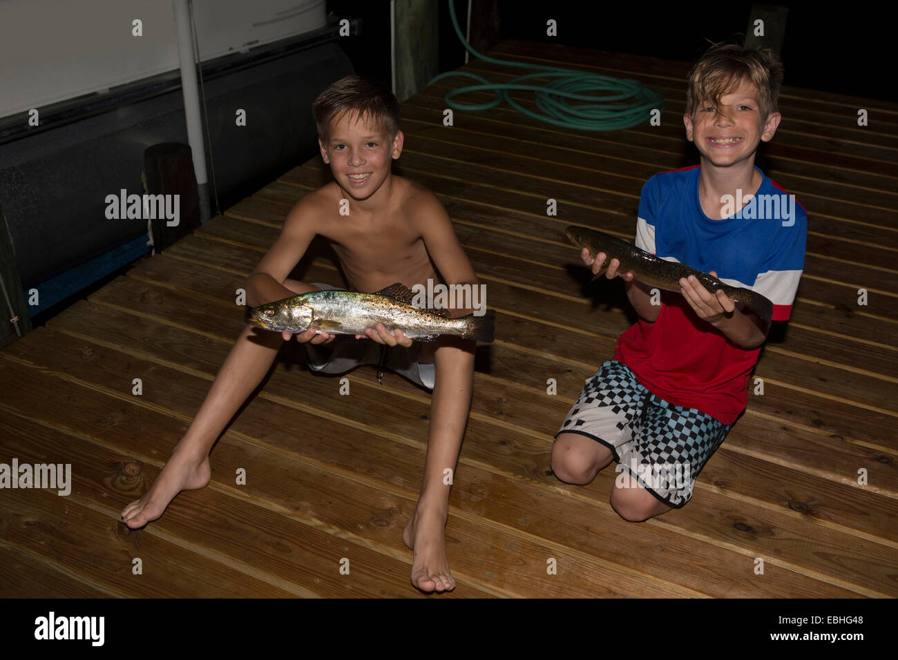 Deux frères sur la jetée de nuit tenant le maquereau espagnol poisson, Shalimar, Florida, USA Banque D'Images
