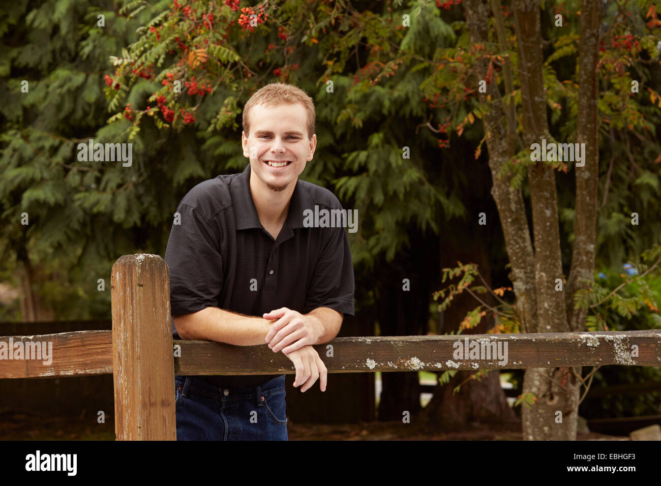 Young man leaning against clôture en bois en forêt Banque D'Images
