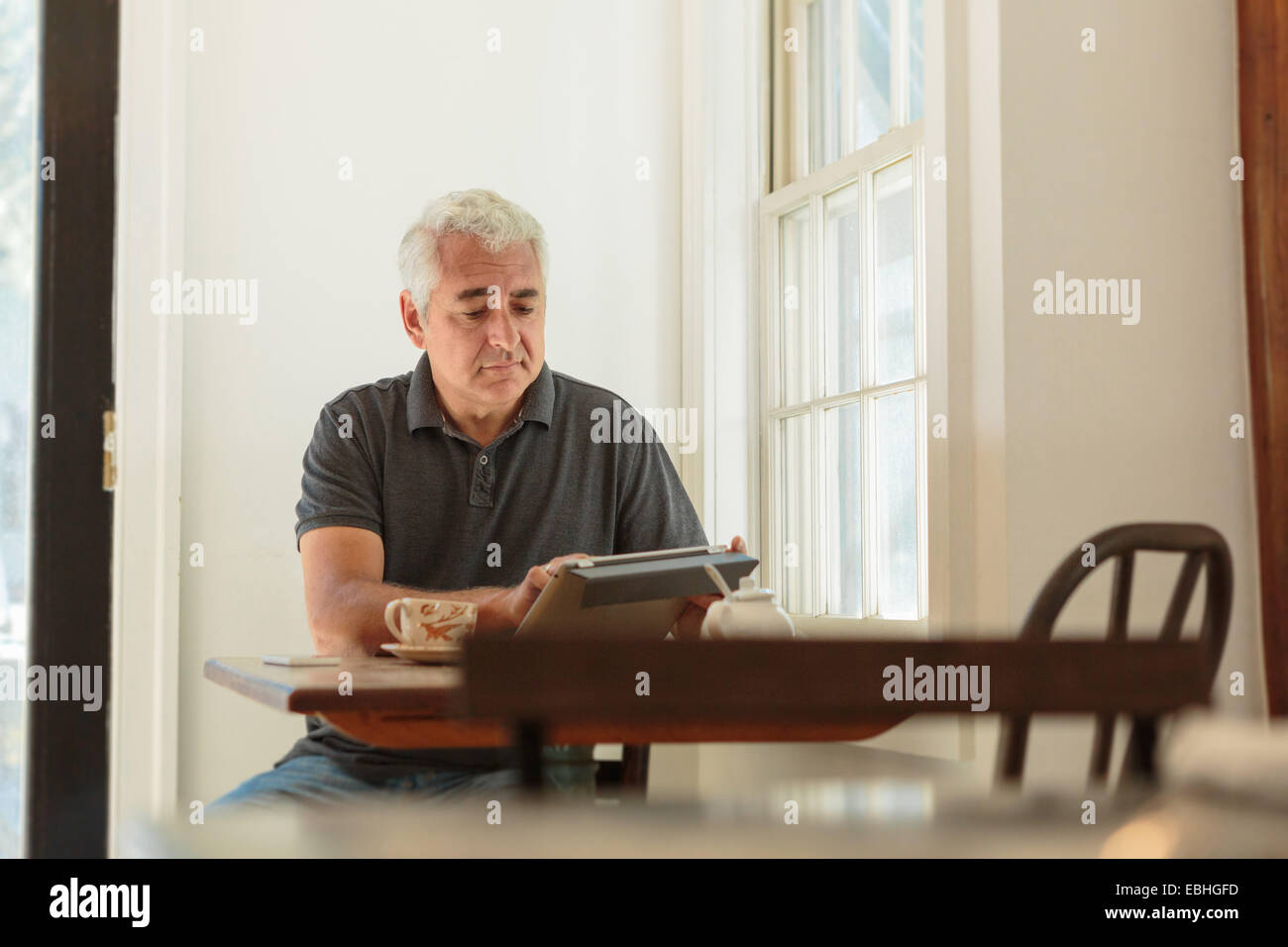 Mature man using digital tablet in country store cafe Banque D'Images
