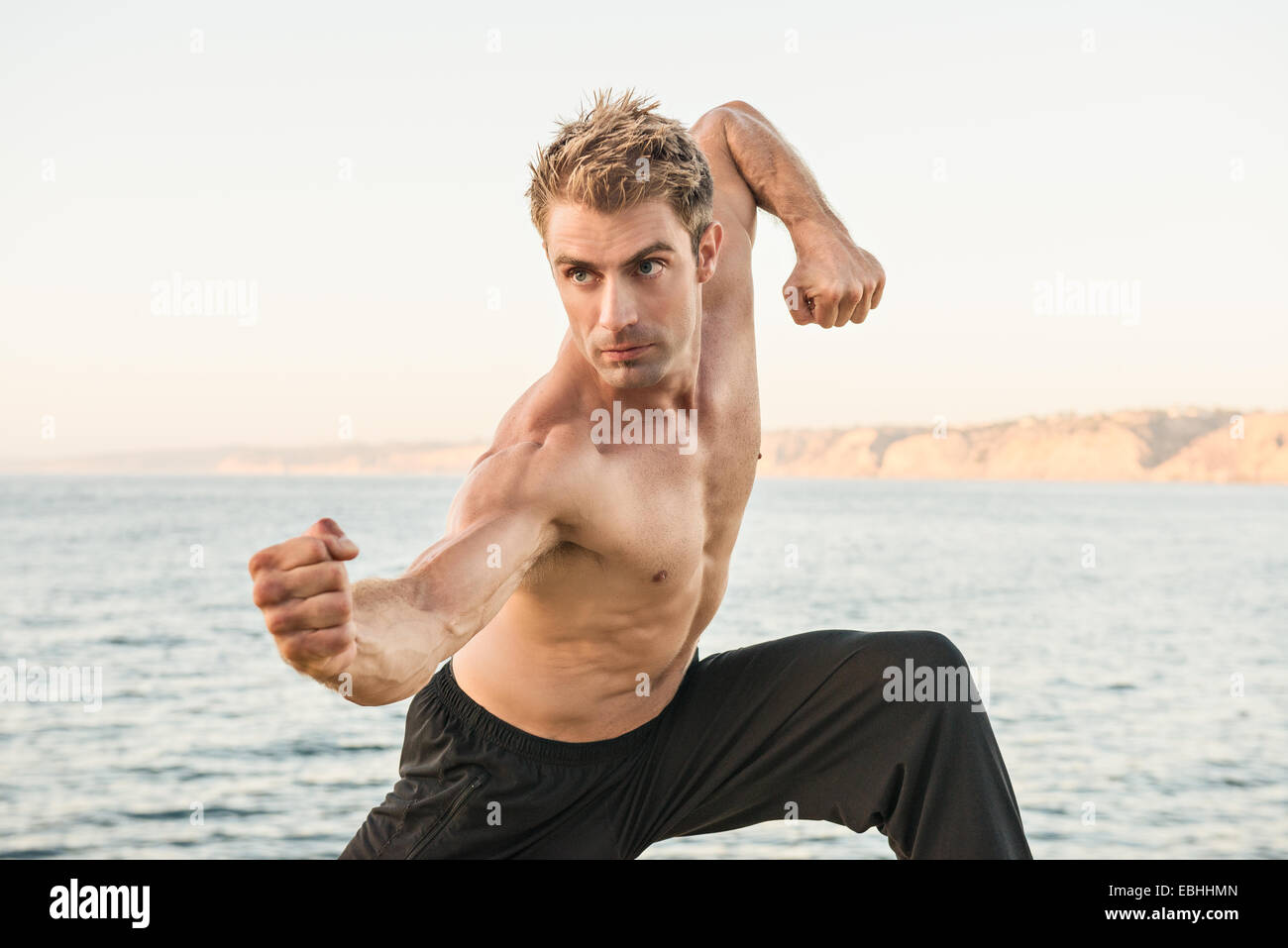Mid adult man on beach dans le kung fu poser Banque D'Images